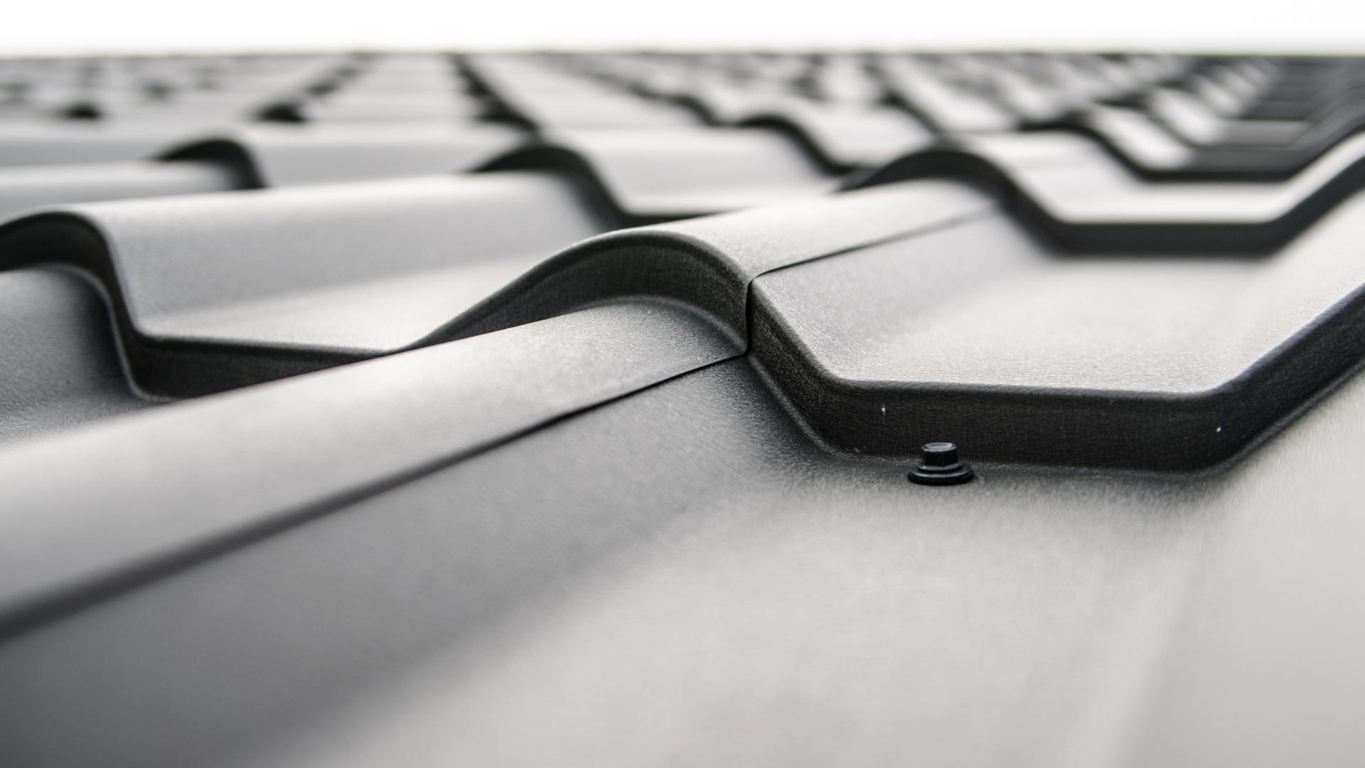 A close up of a black tile roof on a white background.