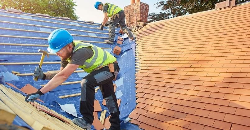 Two men are working on the roof of a house.