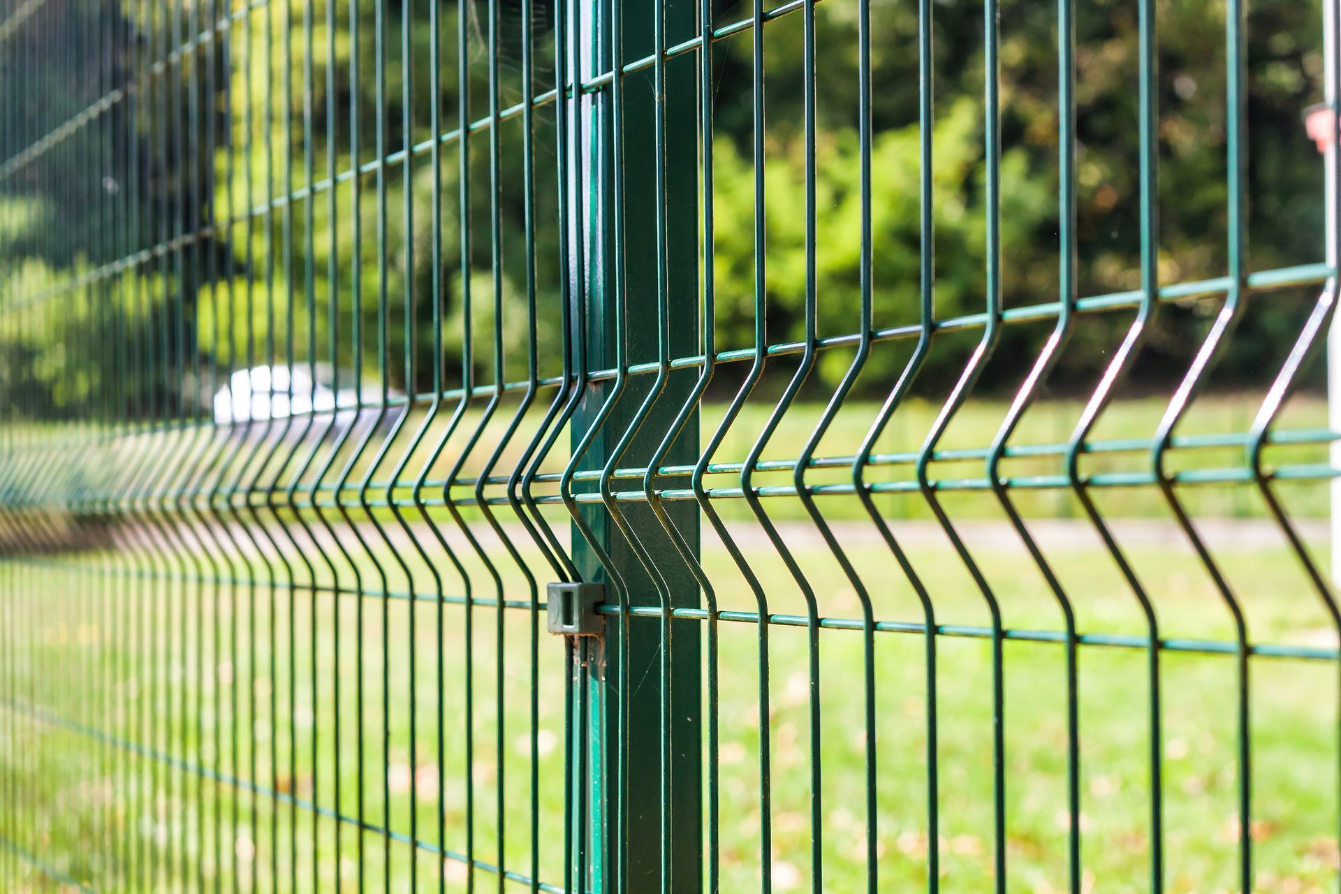 Close-up of green grating wire, with a blurry background of a park.