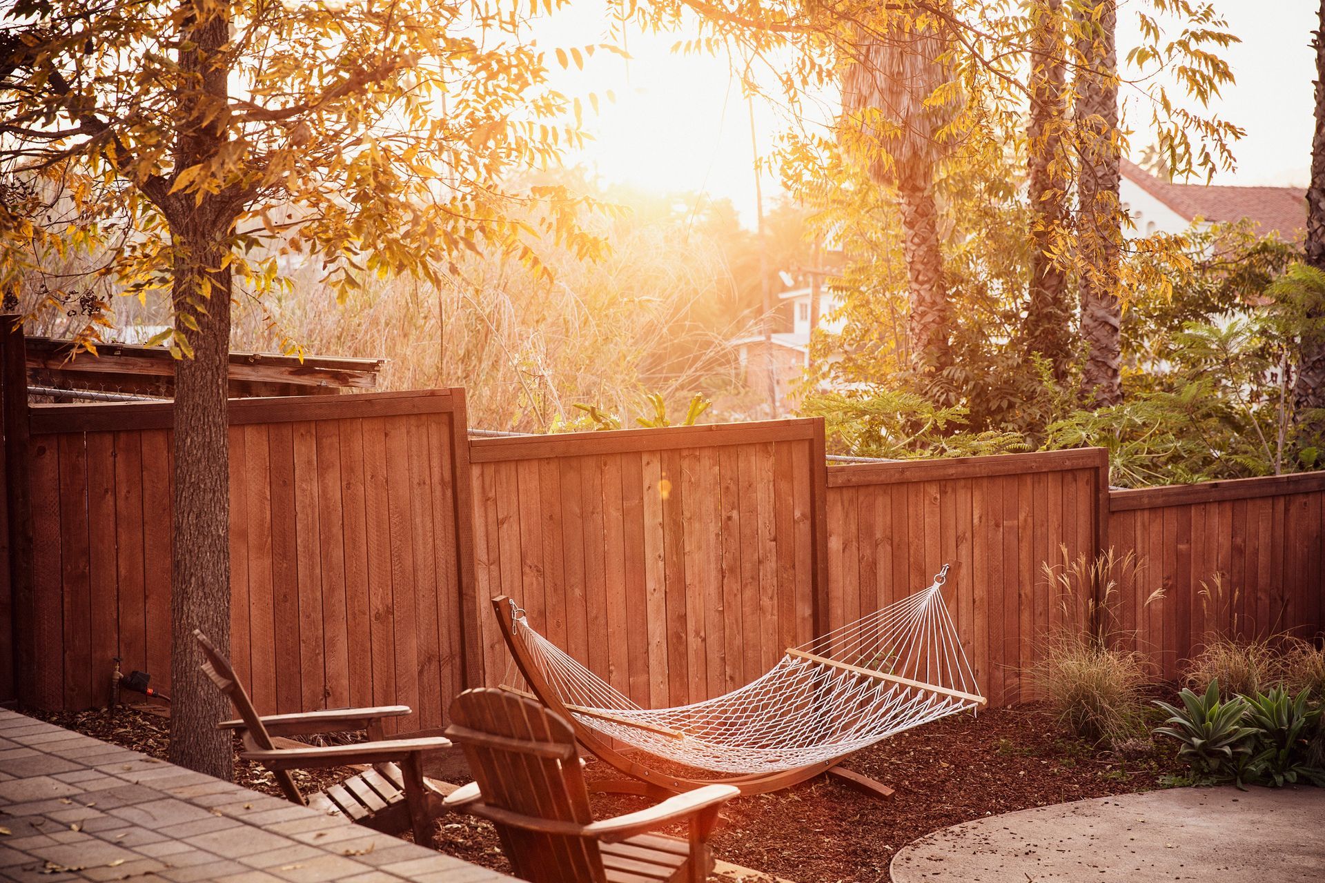 A hammock is sitting in front of a wooden fence.