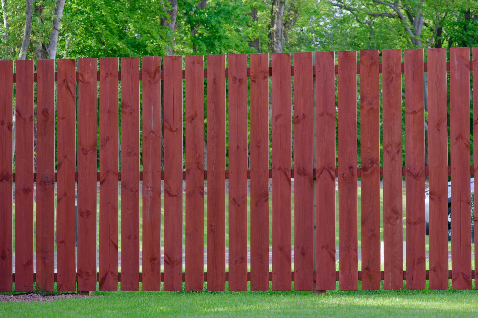 A red wooden fence is sitting on top of a lush green lawn.