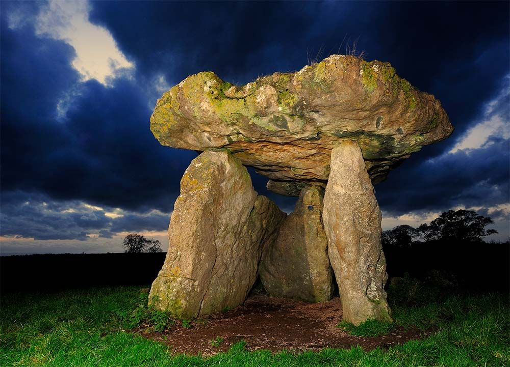 A South Wales tumulus at night featuring one large rock standing on three uprights