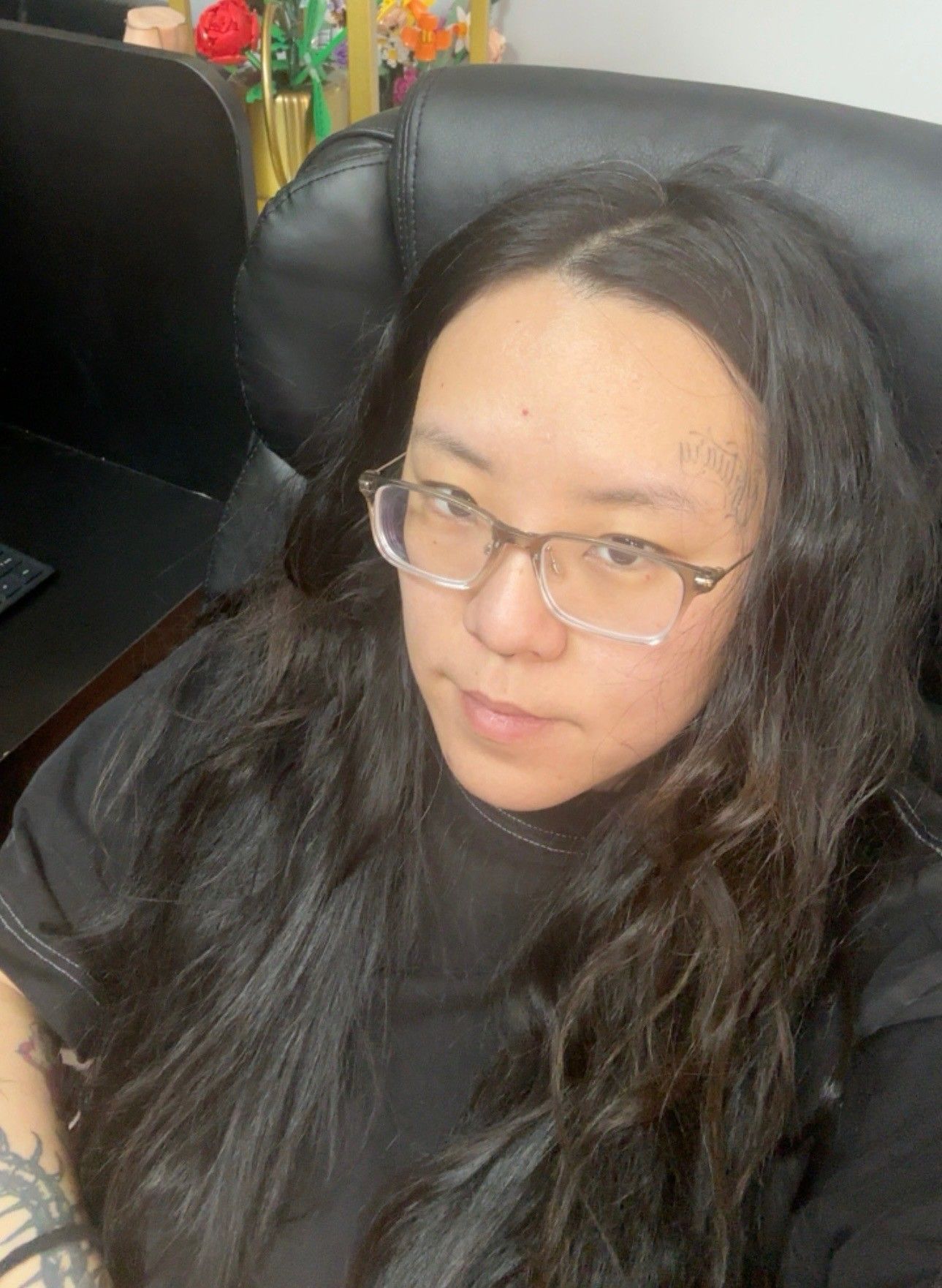 Woman with blonde hair wearing a black off-shoulder top, smiles inside a restaurant.