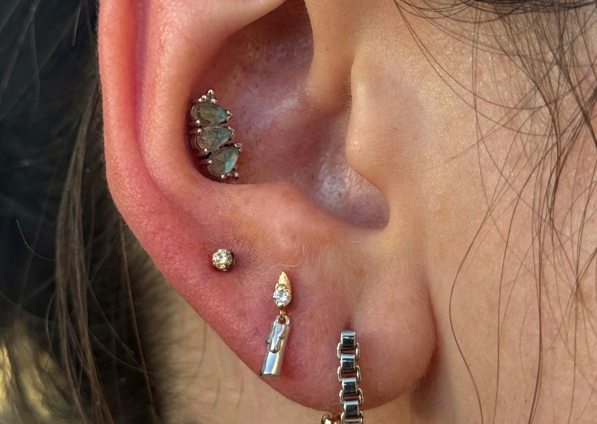 A close up of a woman 's nose with multiple piercings.- Manhattan, NY - Studio 28 Tattoo