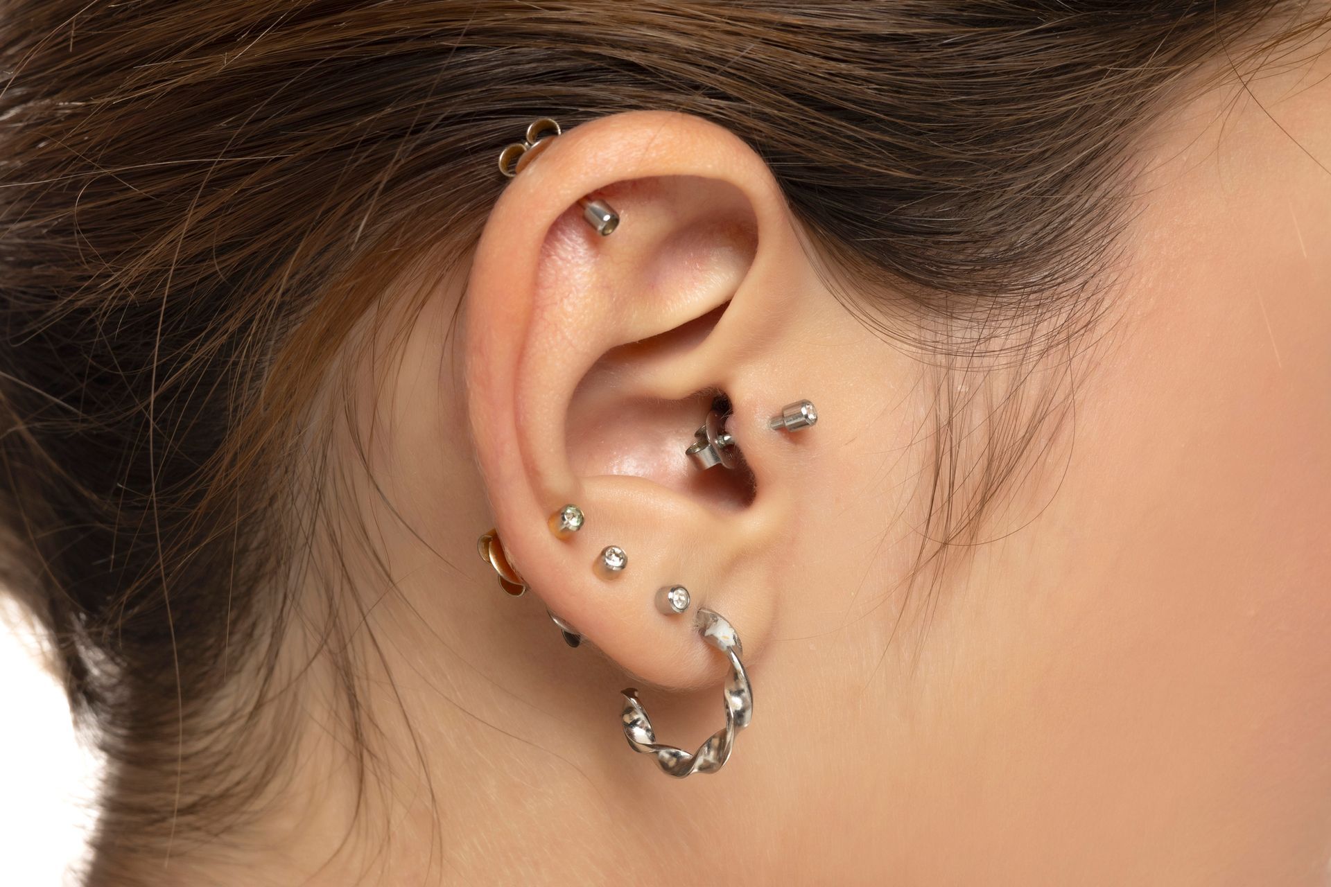 Close-up of a woman’s ear featuring a curated piercing arrangement.