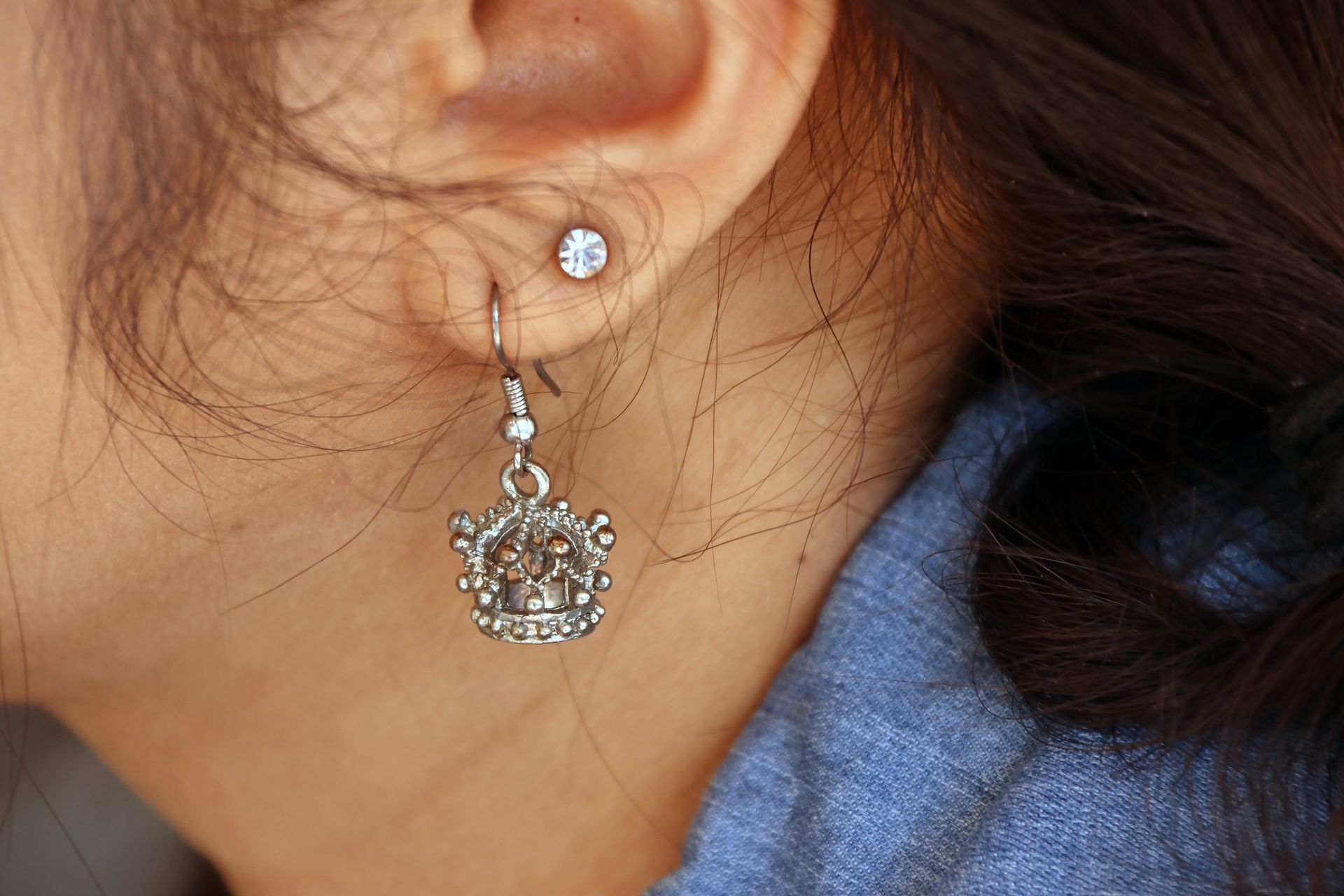 Crown-shaped metal earring with a diamond accent on the ear, showcasing stylish ear curation from St