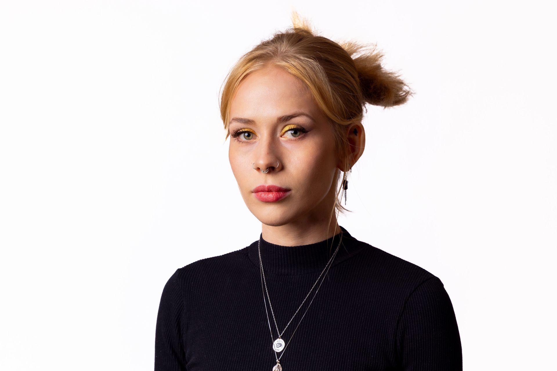 Man with curly hair and tattoos smiles, hands in pockets, wearing a navy polo and khaki pants.