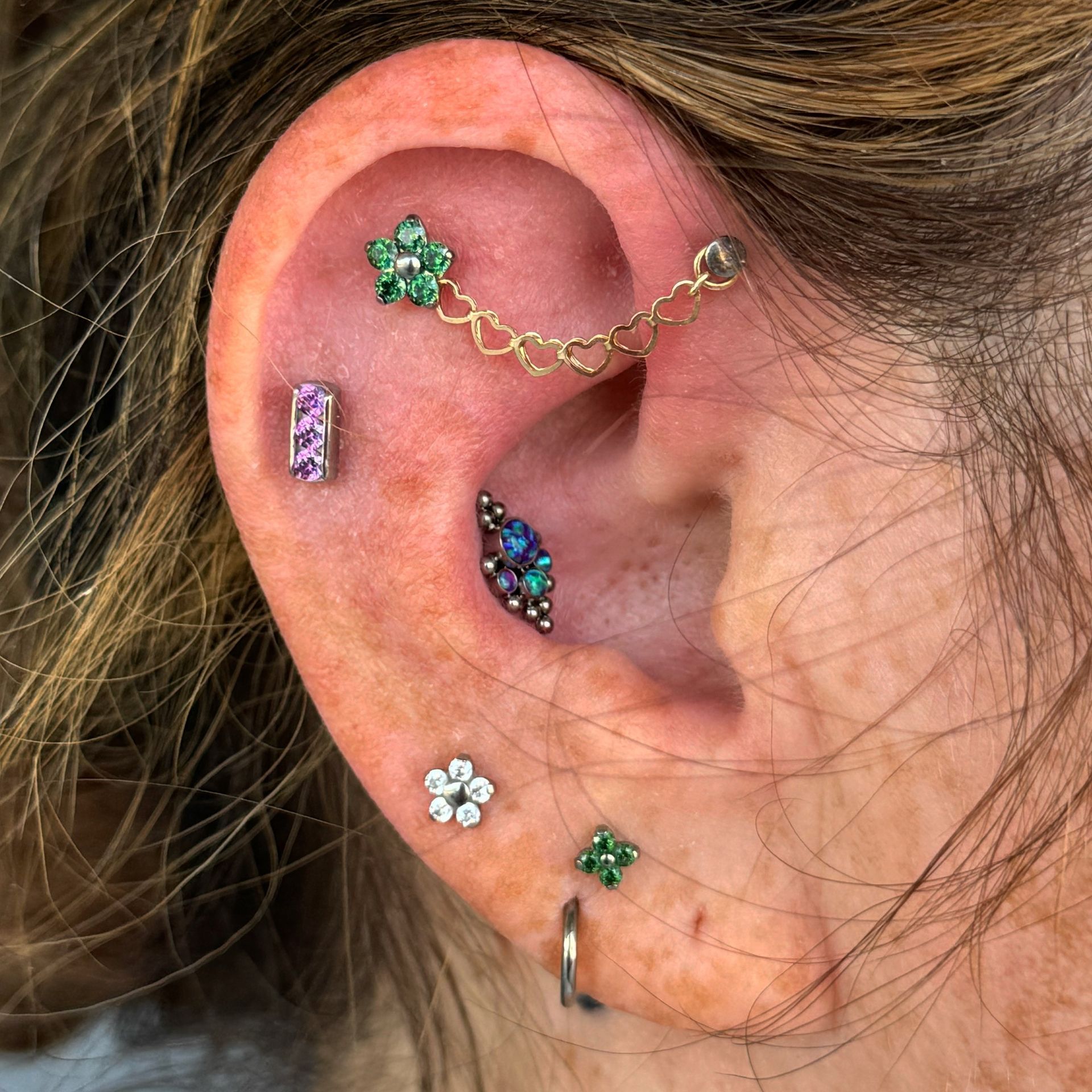 A close up of a woman 's ear with multiple piercings - Manhattan, NY - Studio 28 Tattoo