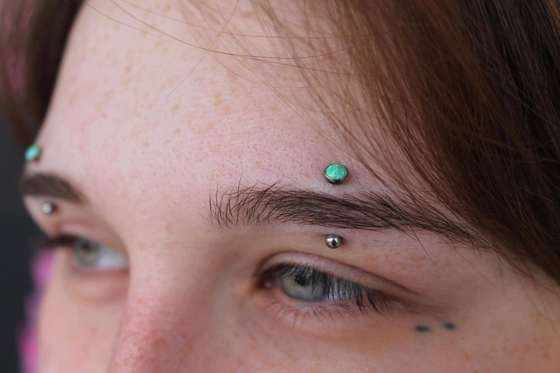 A close up of a woman 's nose with a nose ring and glasses. - Manhattan, NY - Studio 28 Tattoo