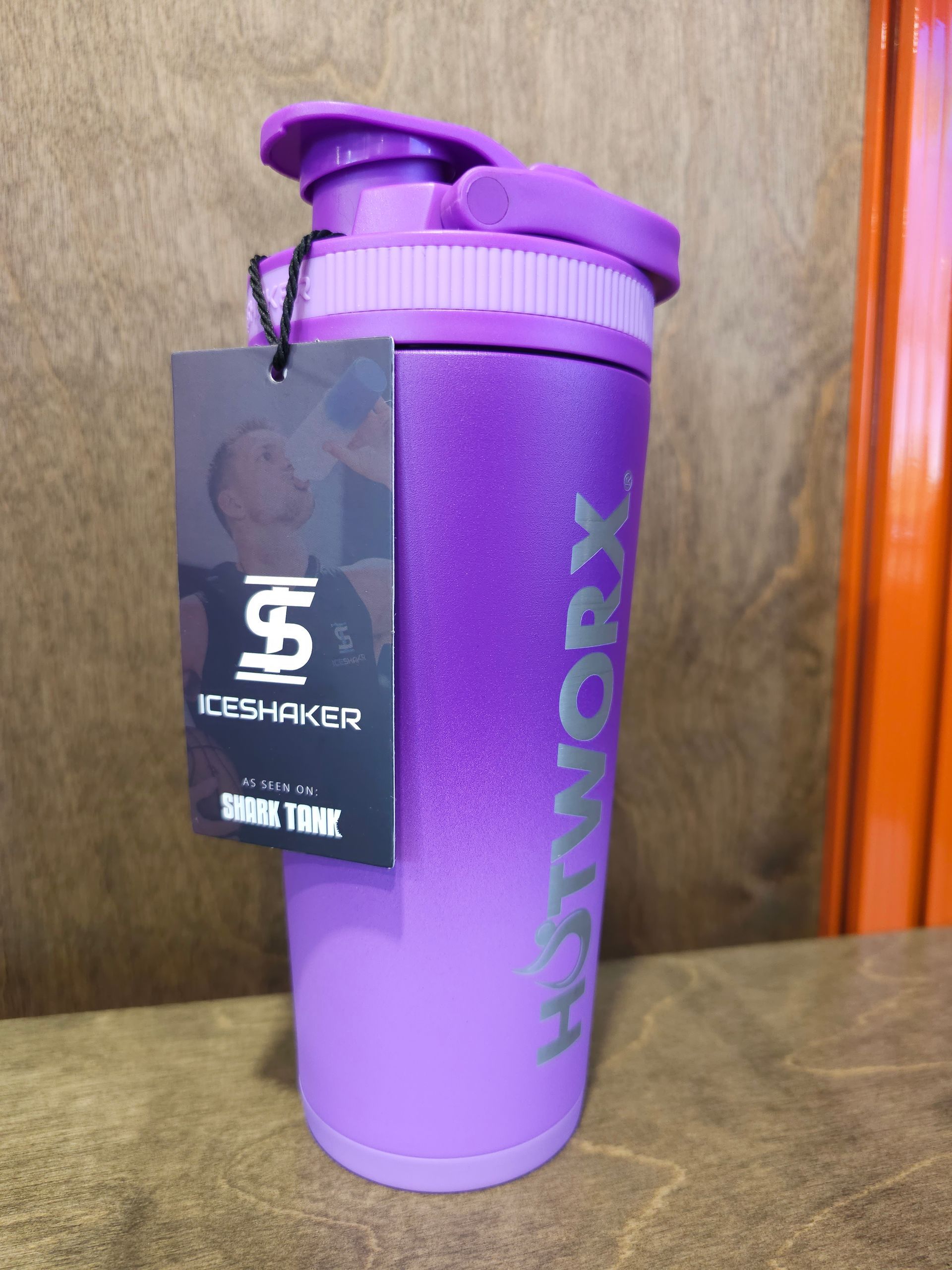 Purple Ice Shaker water bottle with HOTWORX logo and attached tag, on a wooden surface.