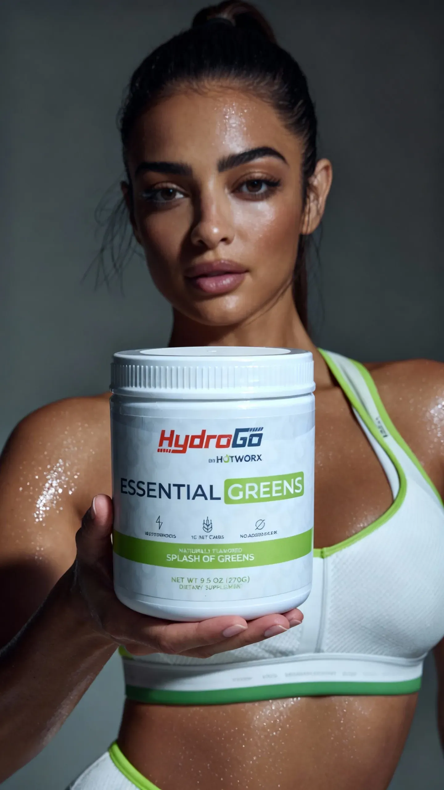 Woman holding Hydro-Lab Essential Greens container, wearing workout clothes, with a sweaty appearance.