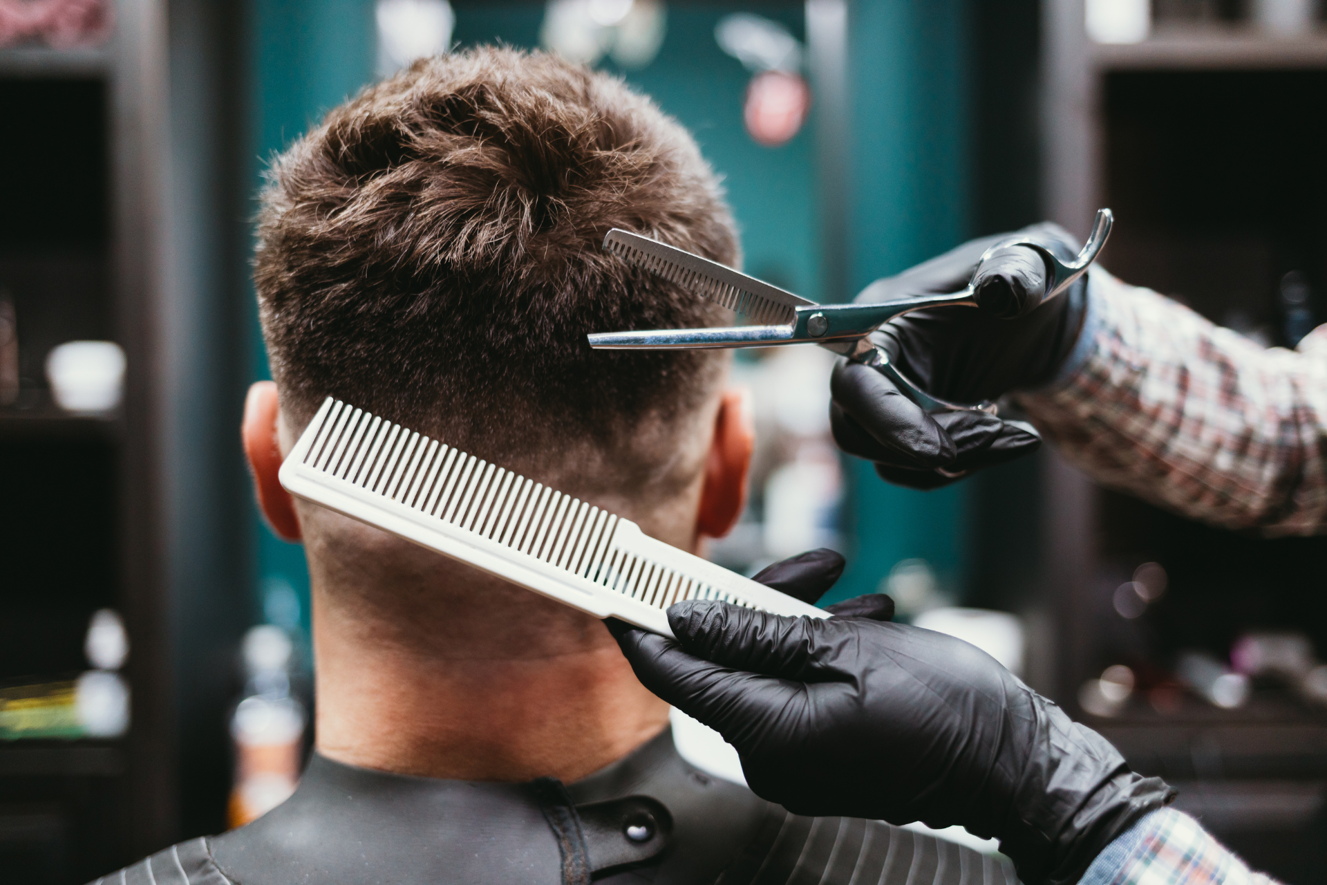 Ein Friseur schneidet einem Mann in einem Friseursalon die Haare; Schere und Kamm werden verwendet.