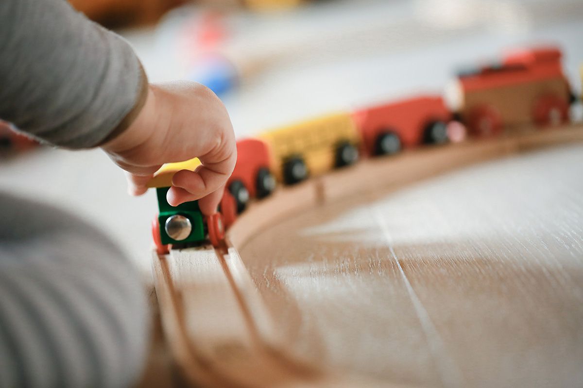 A child is playing with a wooden train set.