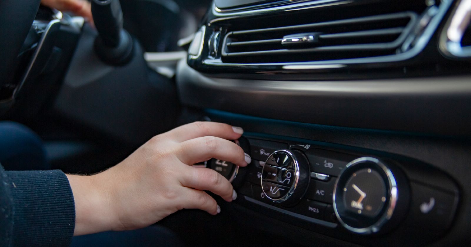 A person is adjusting the air conditioning in a car.