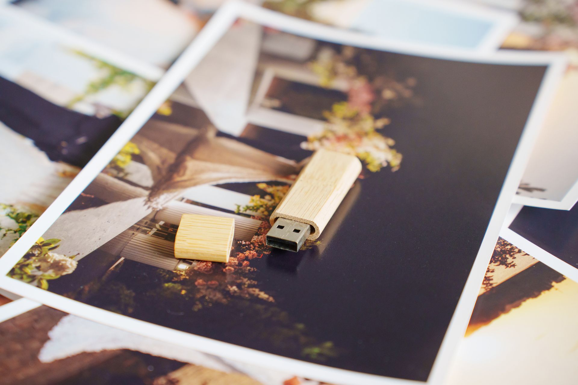 Chiavetta USB con tappo accanto, sopra diverse foto stampate.