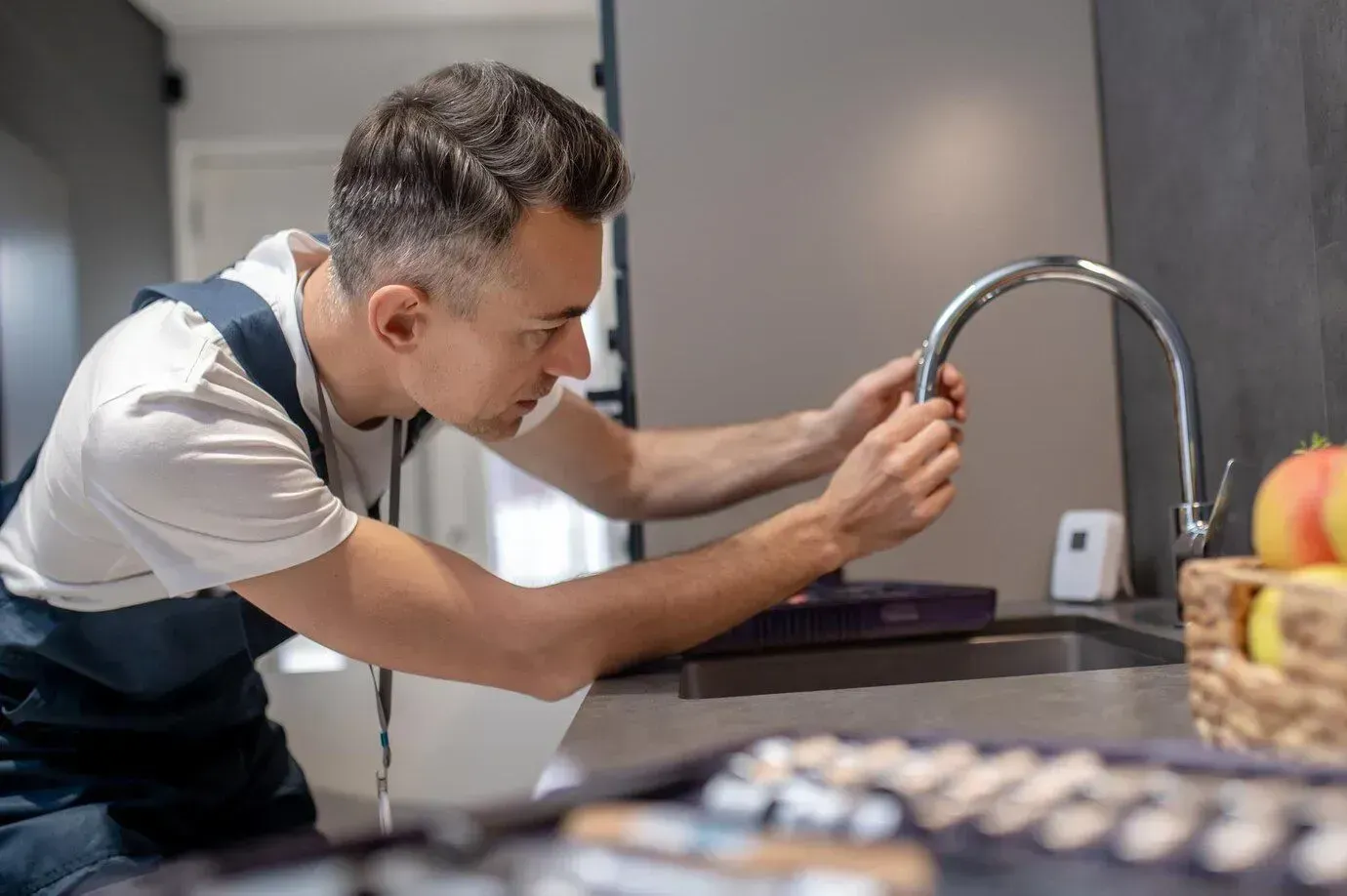 A man is fixing a faucet in a kitchen.