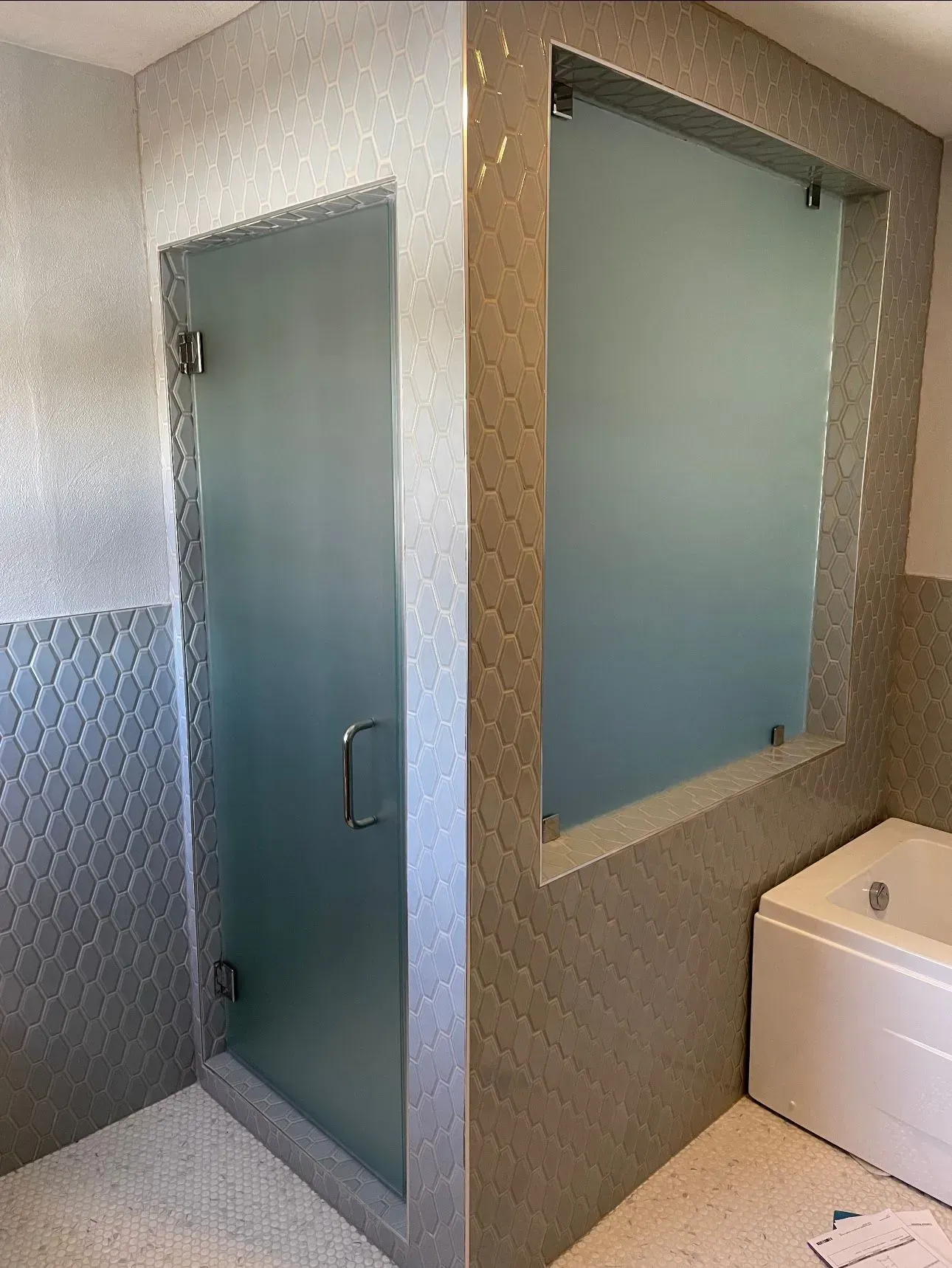 A bathroom with a glass shower door and a bathtub.