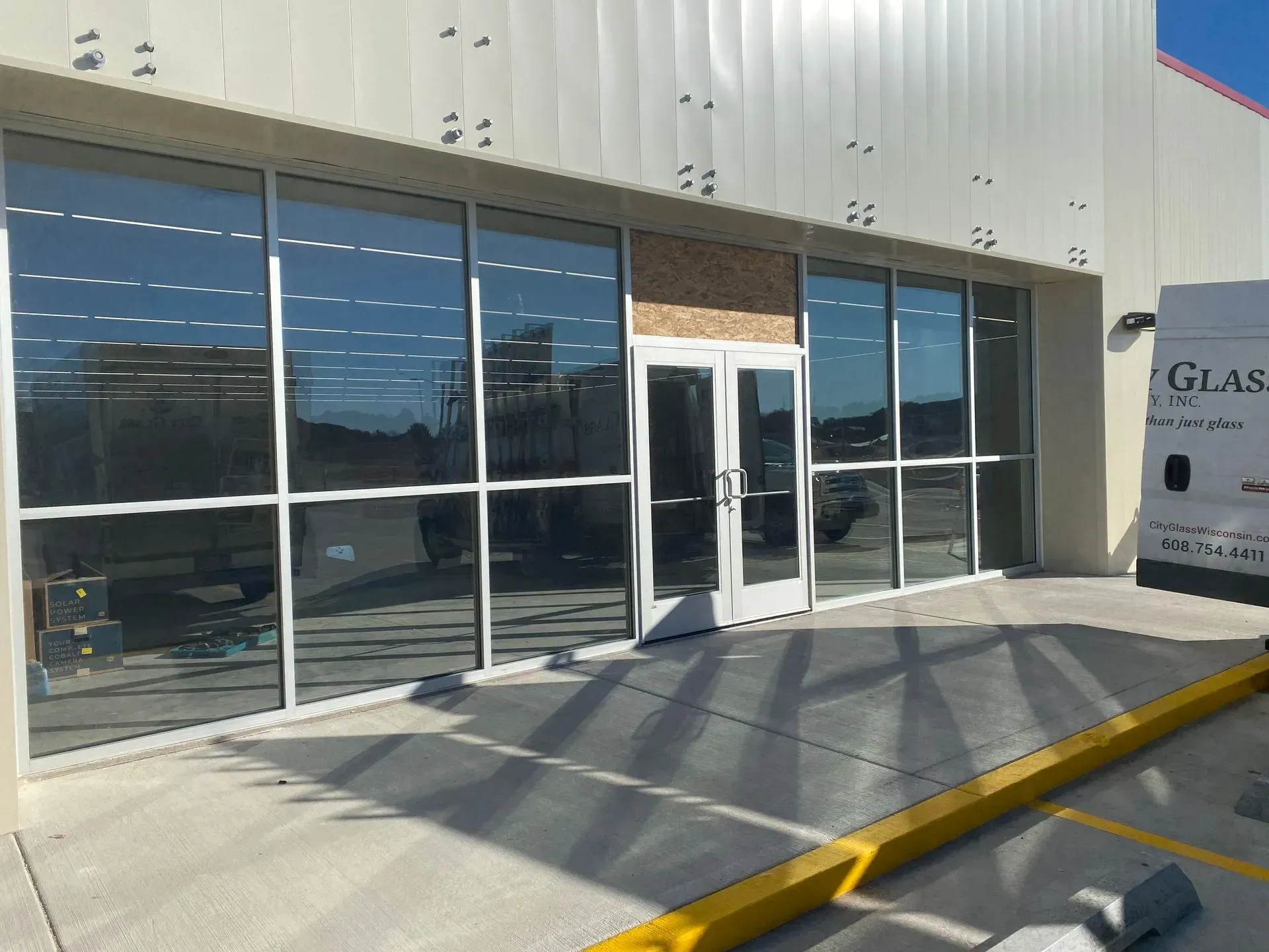 A white van is parked in front of a building with a lot of windows.