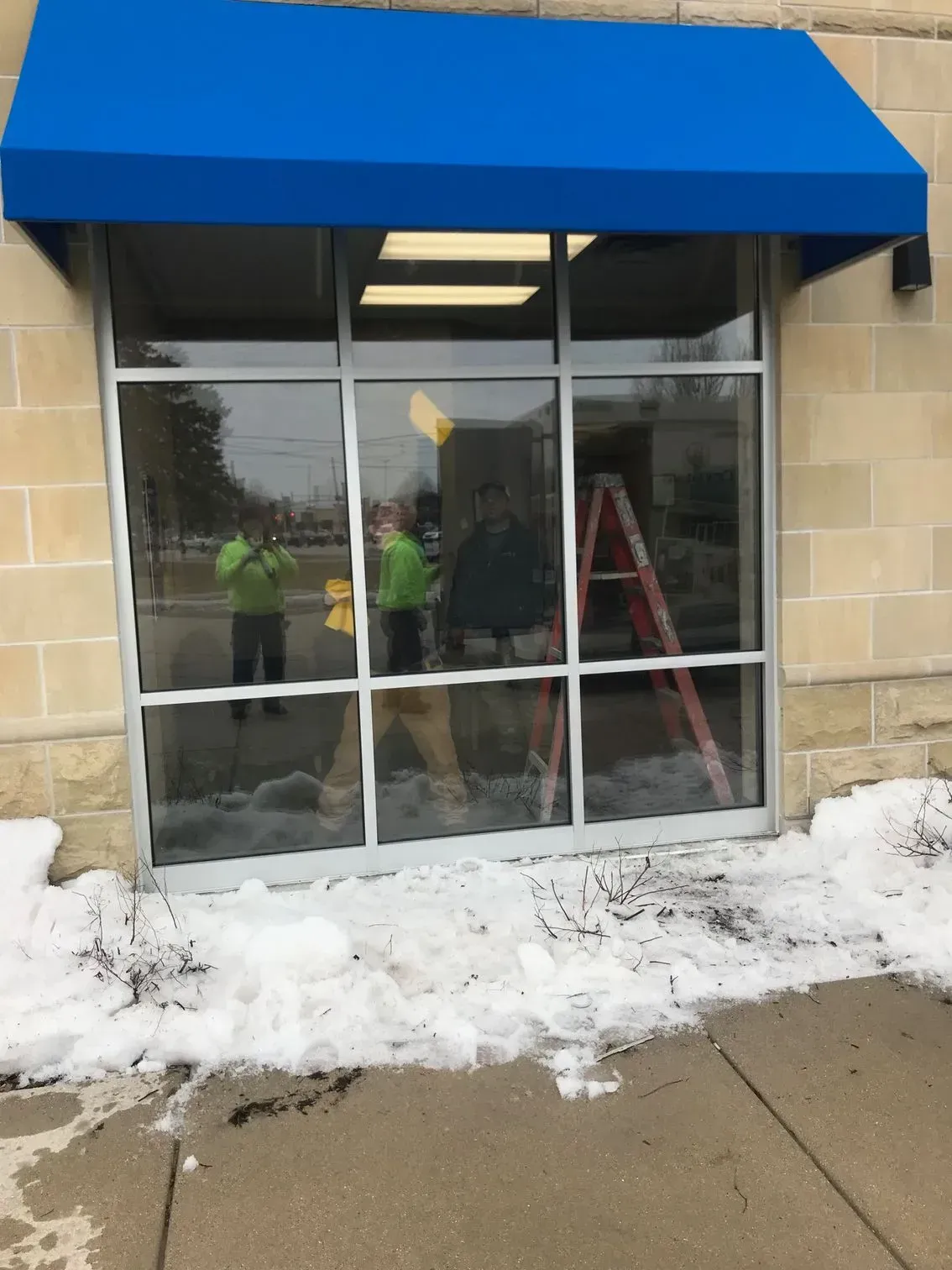 A blue awning is hanging over a glass door.