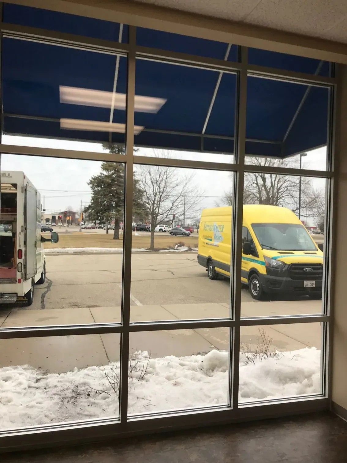 A yellow van is parked in front of a window.