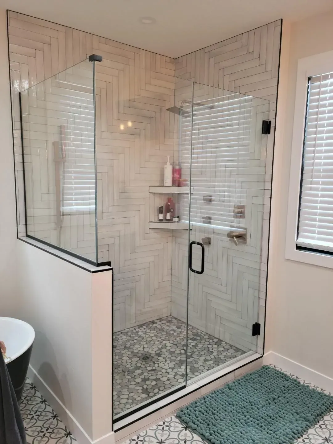 A bathroom with a walk in shower with a glass door.