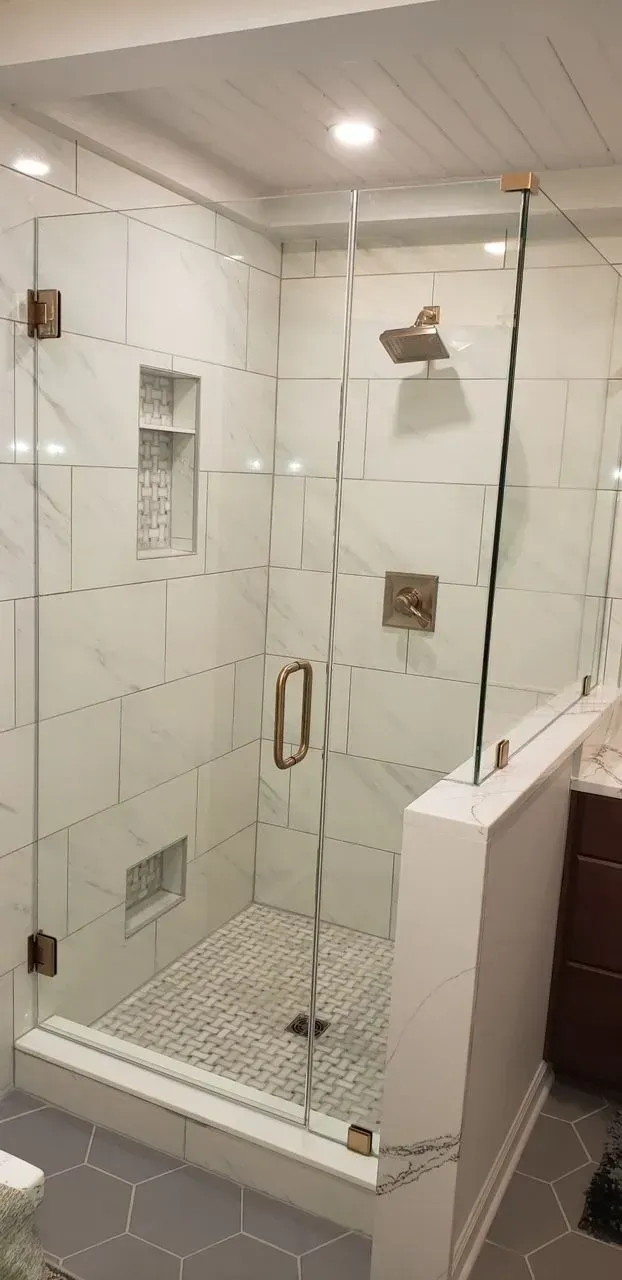 A bathroom with a walk in shower with a glass door.