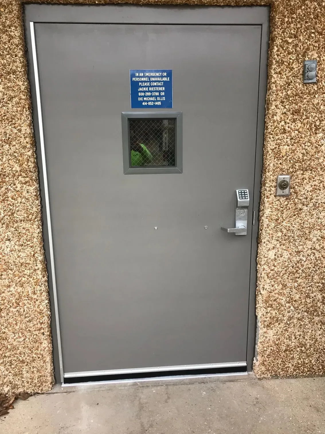 A gray door with a window and a sign on it