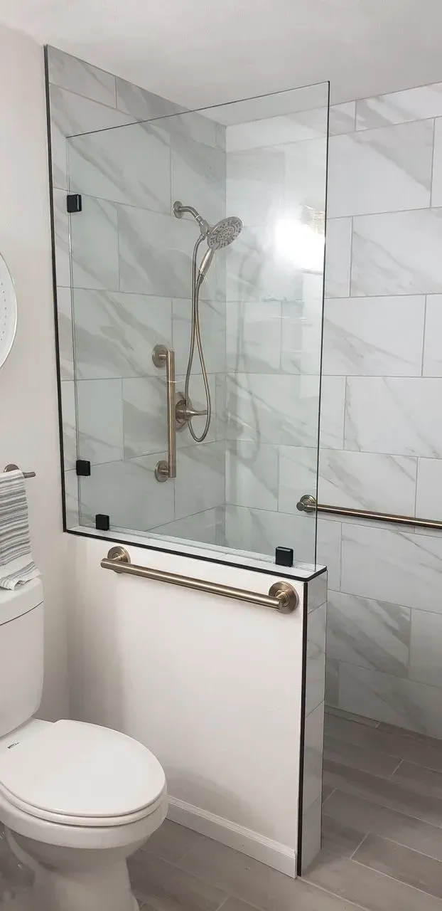 A bathroom with a toilet and a walk in shower with a glass door.