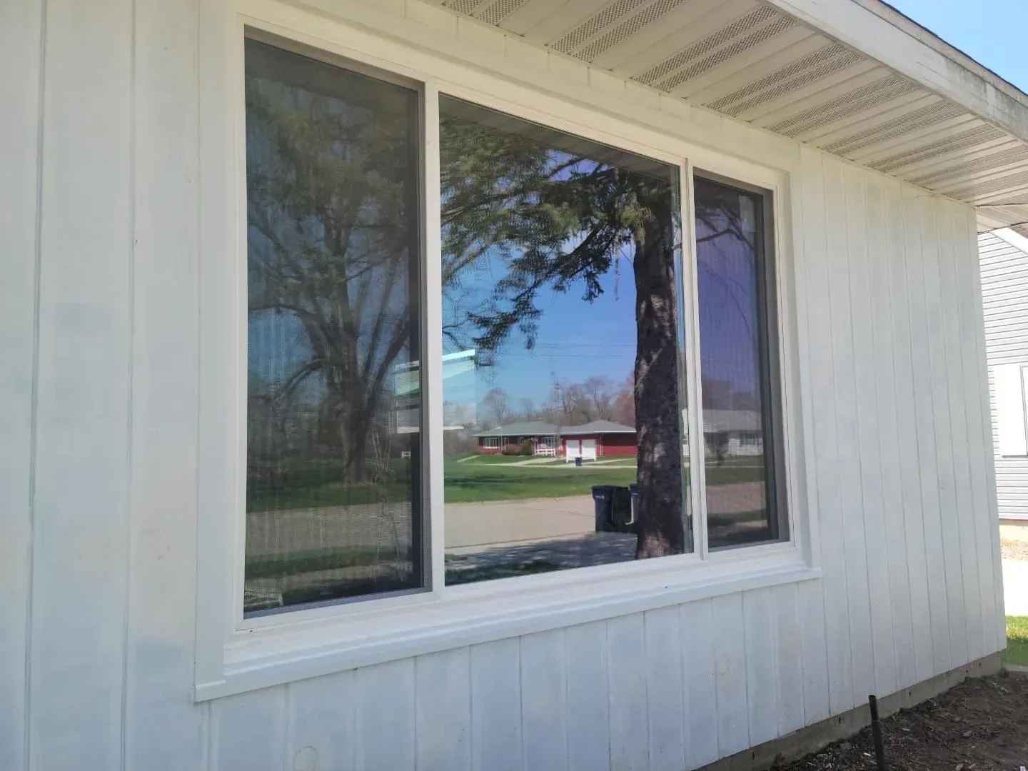 A white house with a large window on the side of it.
