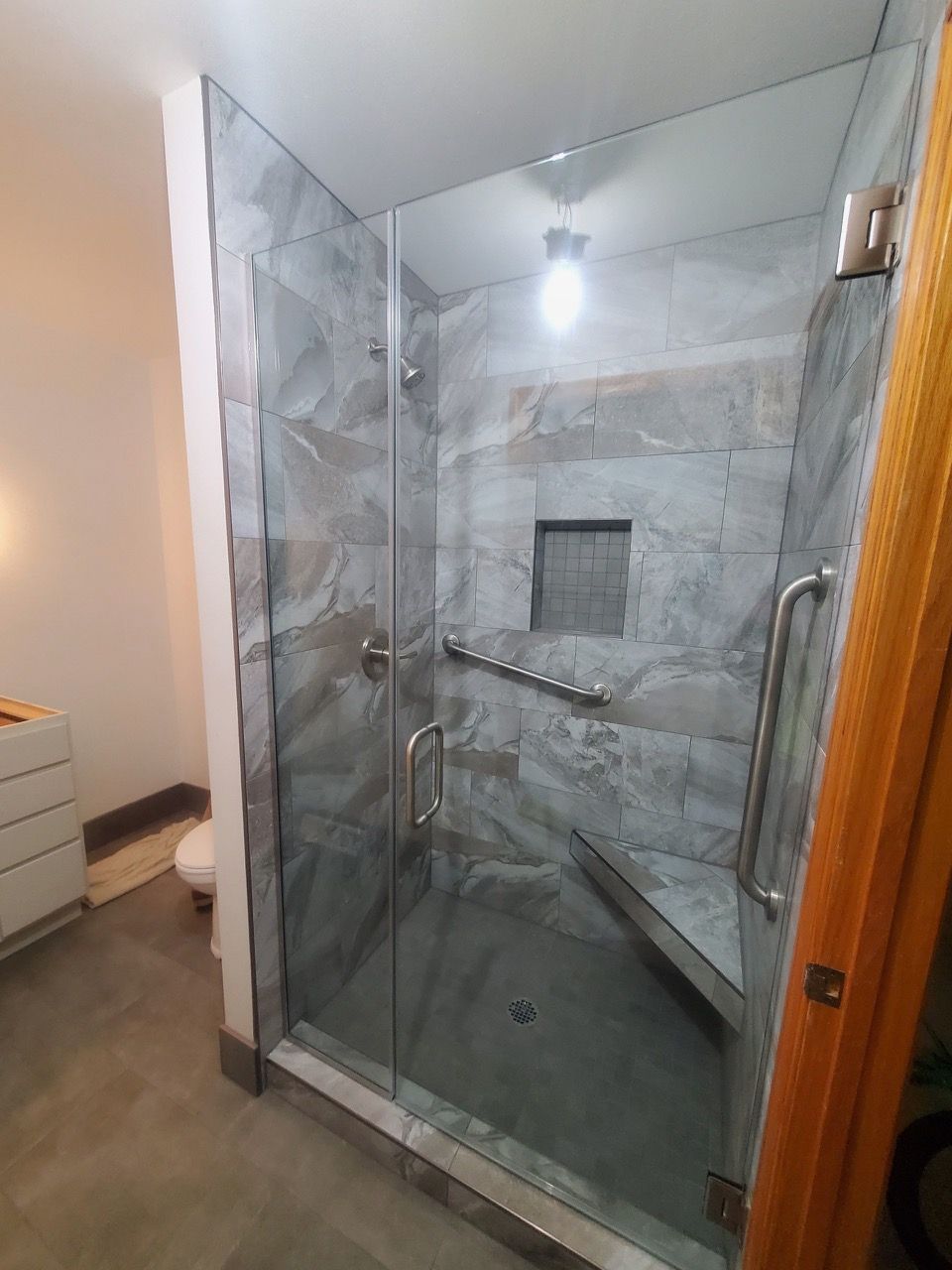 A bathroom with a walk in shower with a glass door.