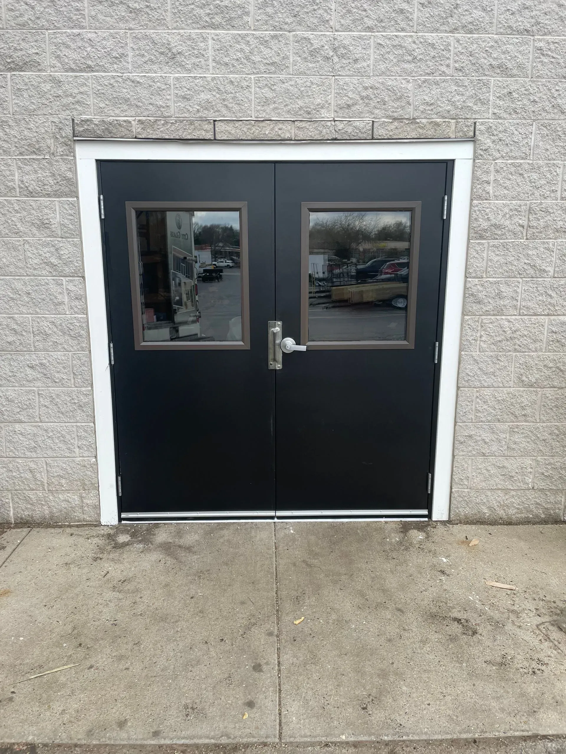 A black double door with two windows on a brick building.