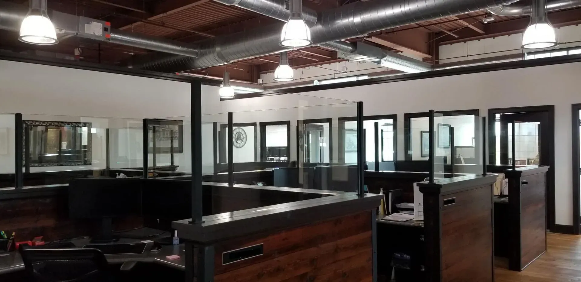 A large room with a lot of cubicles and a lot of windows.