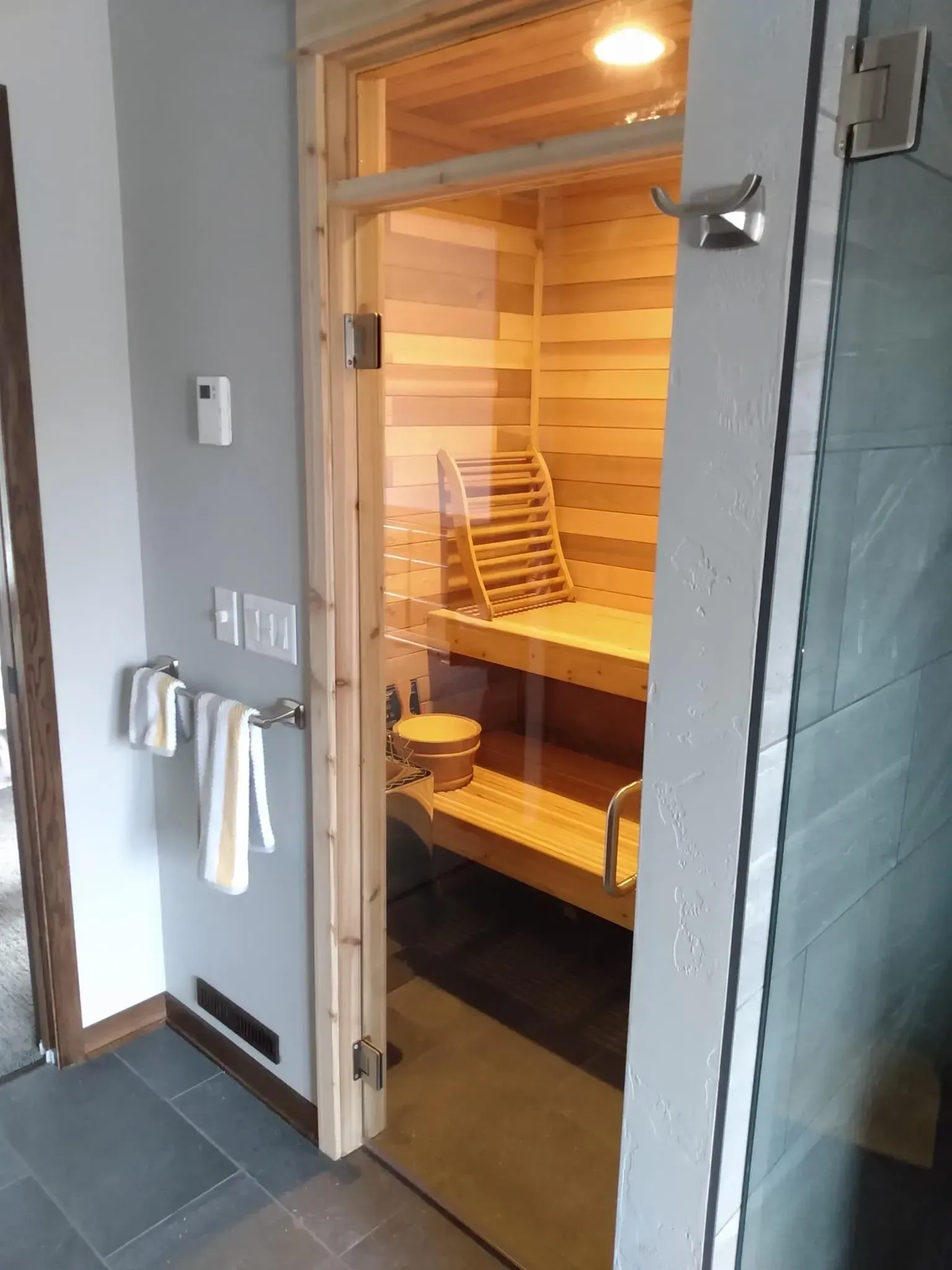 A wooden sauna with a glass door in a bathroom.