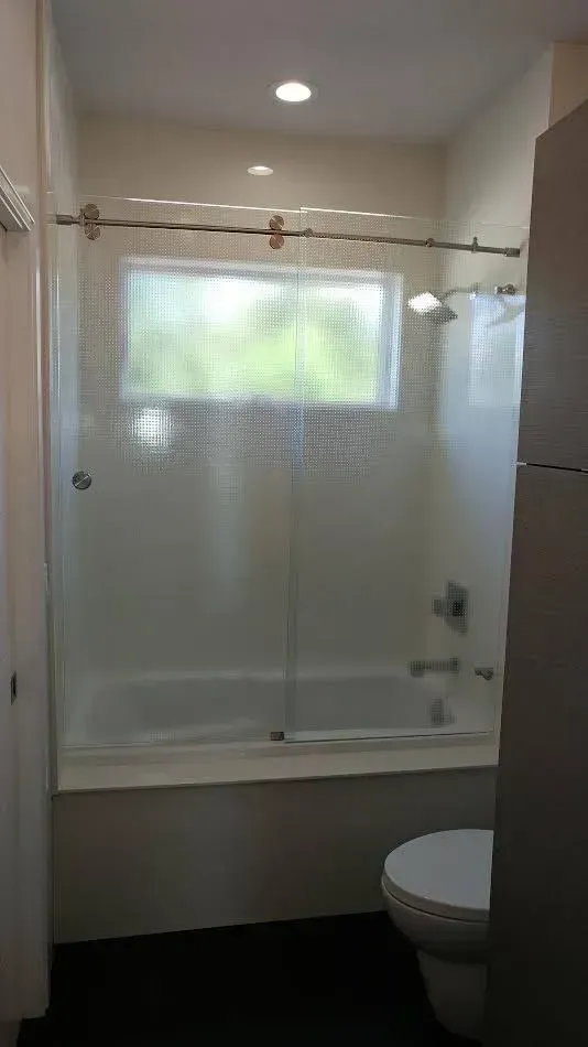 A bathroom with a tub , toilet , shower and window.