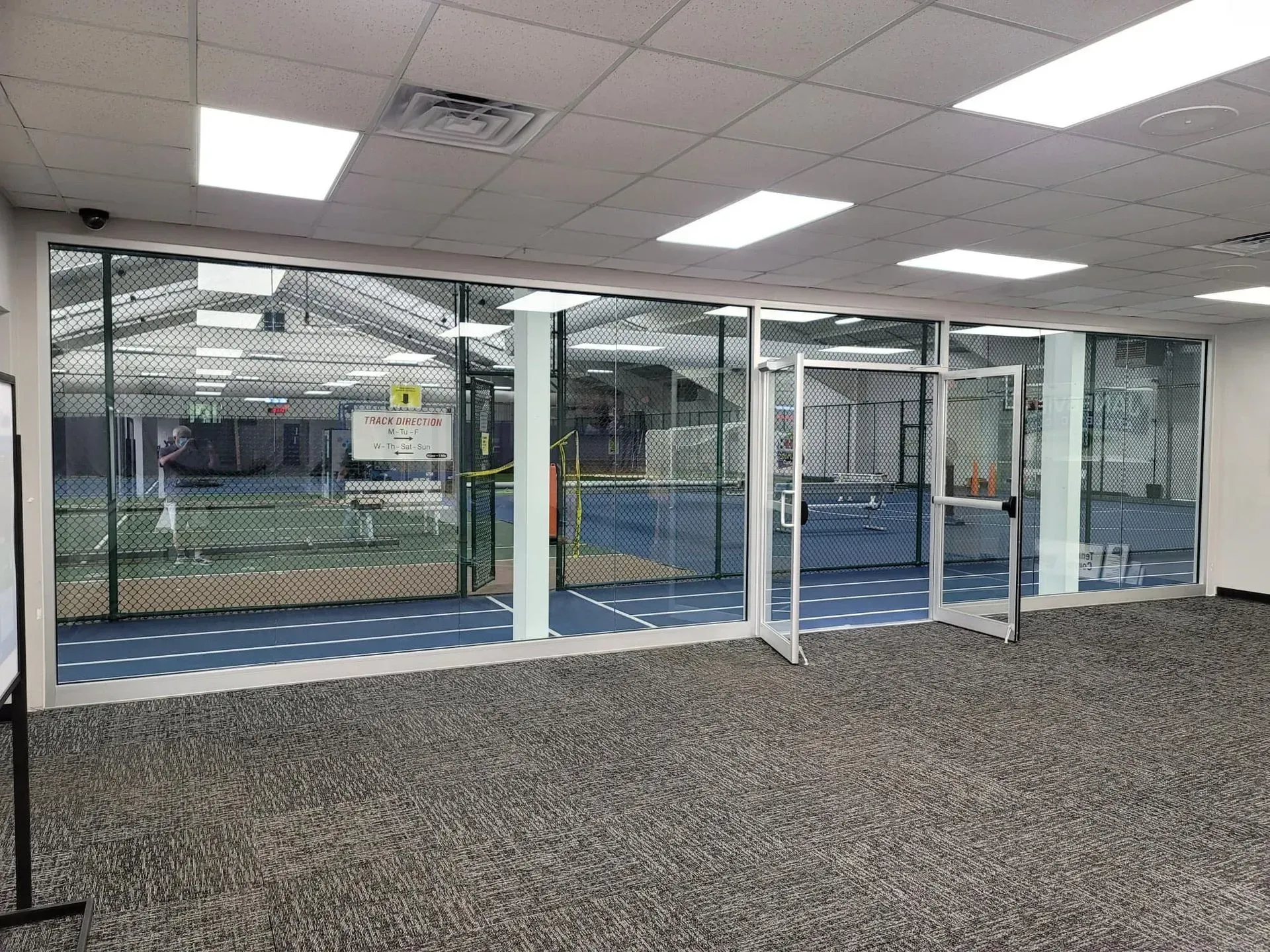 A large room with a lot of windows and a tennis court in the background.