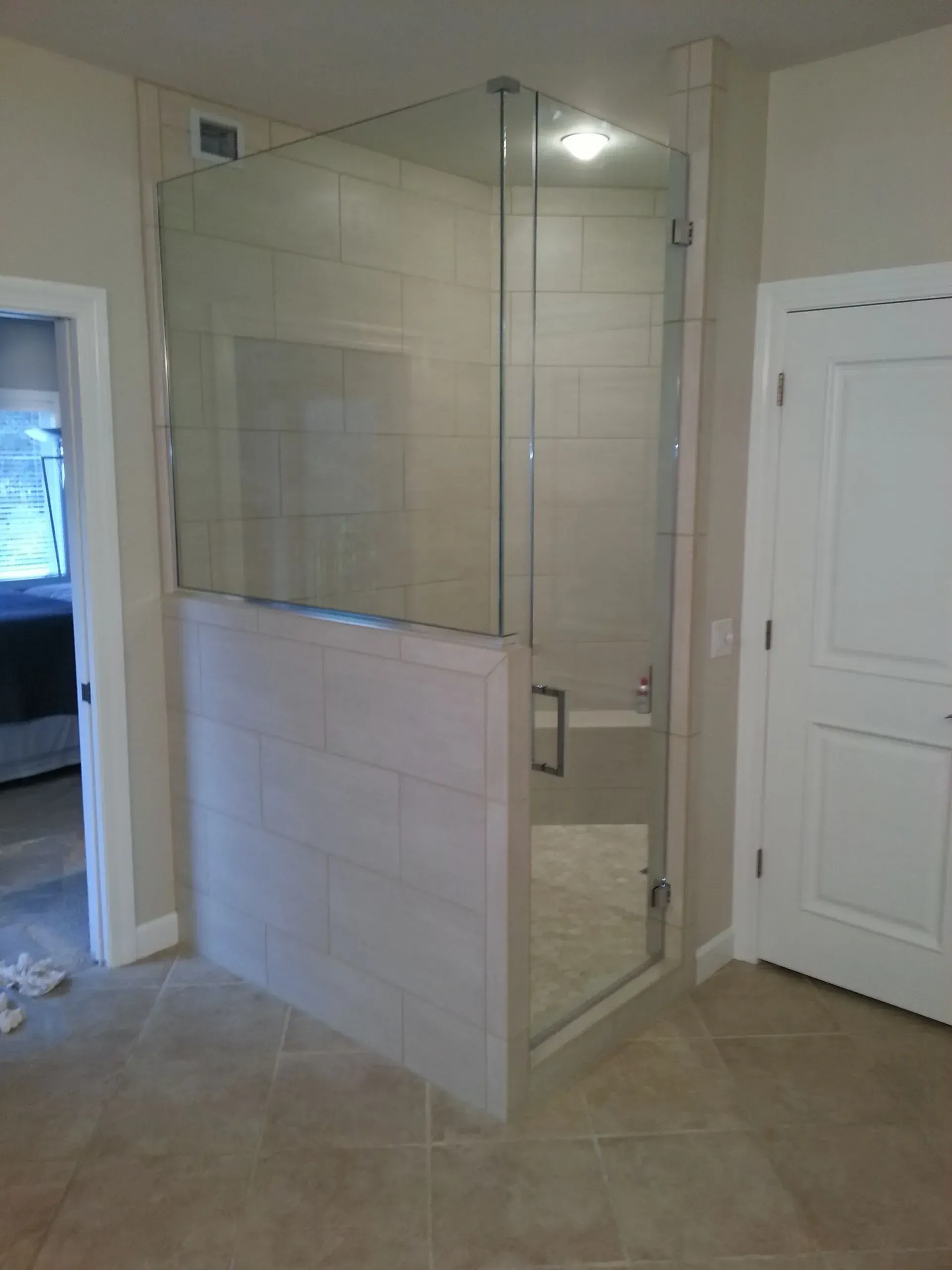 A bathroom with a walk in shower with a glass door