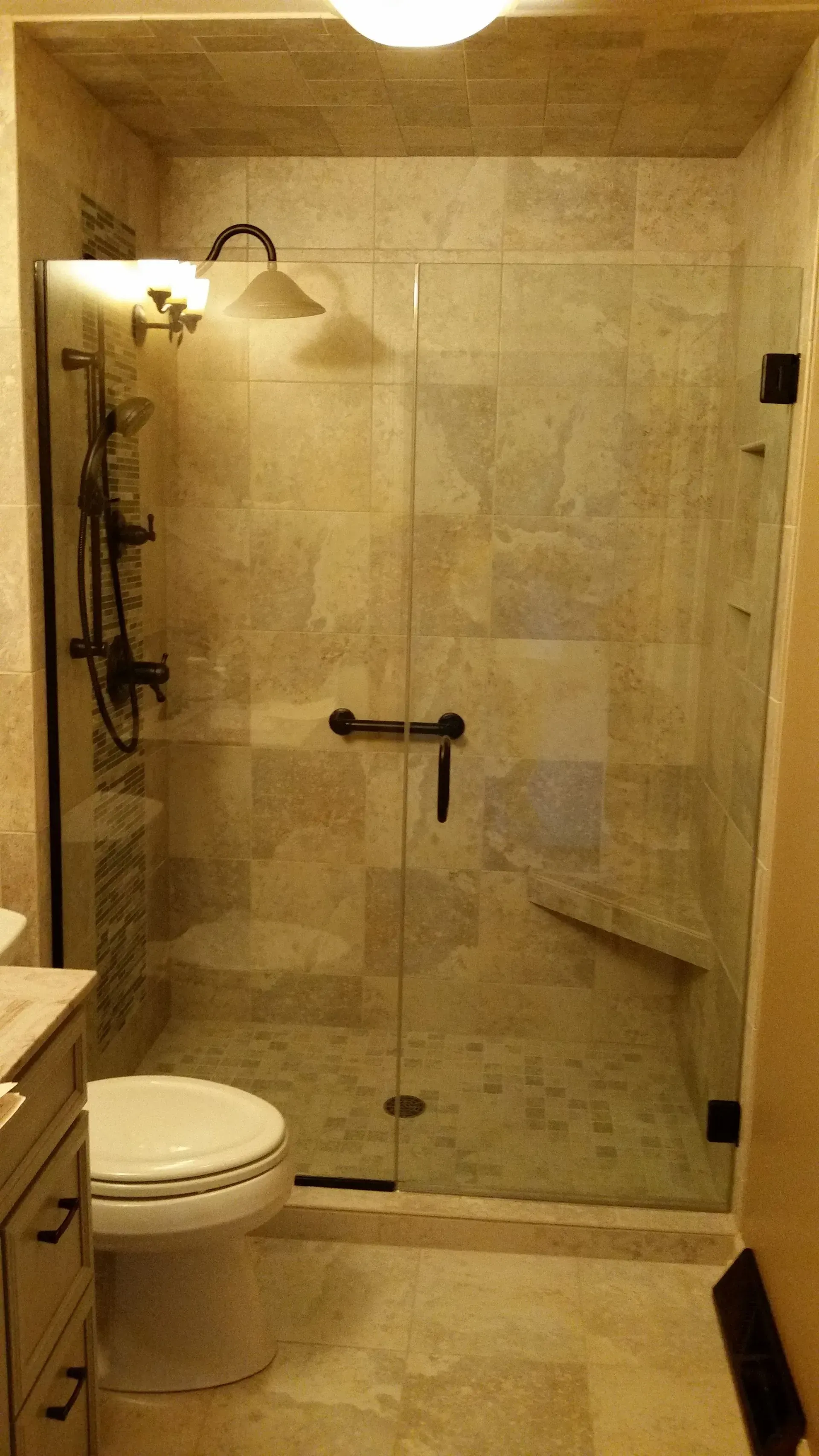 A bathroom with a toilet and a walk in shower with a glass door.