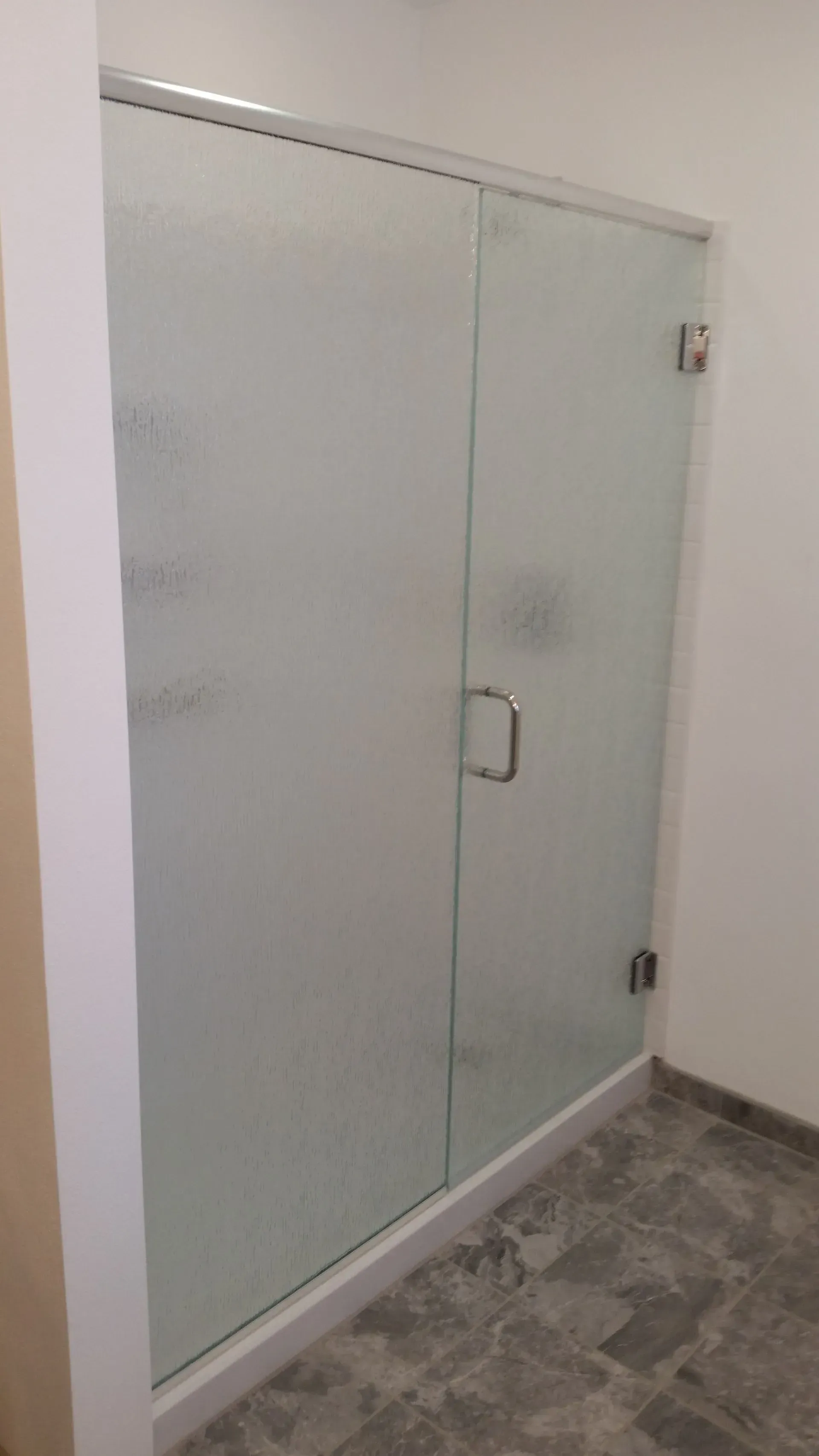 A shower stall with a frosted glass door in a bathroom.