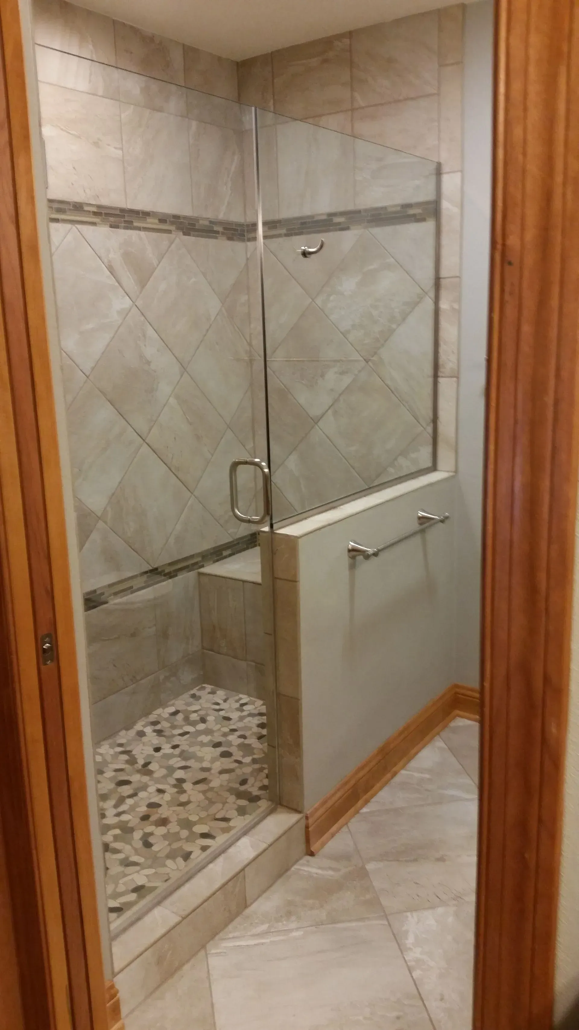 A bathroom with a walk in shower with a glass door.