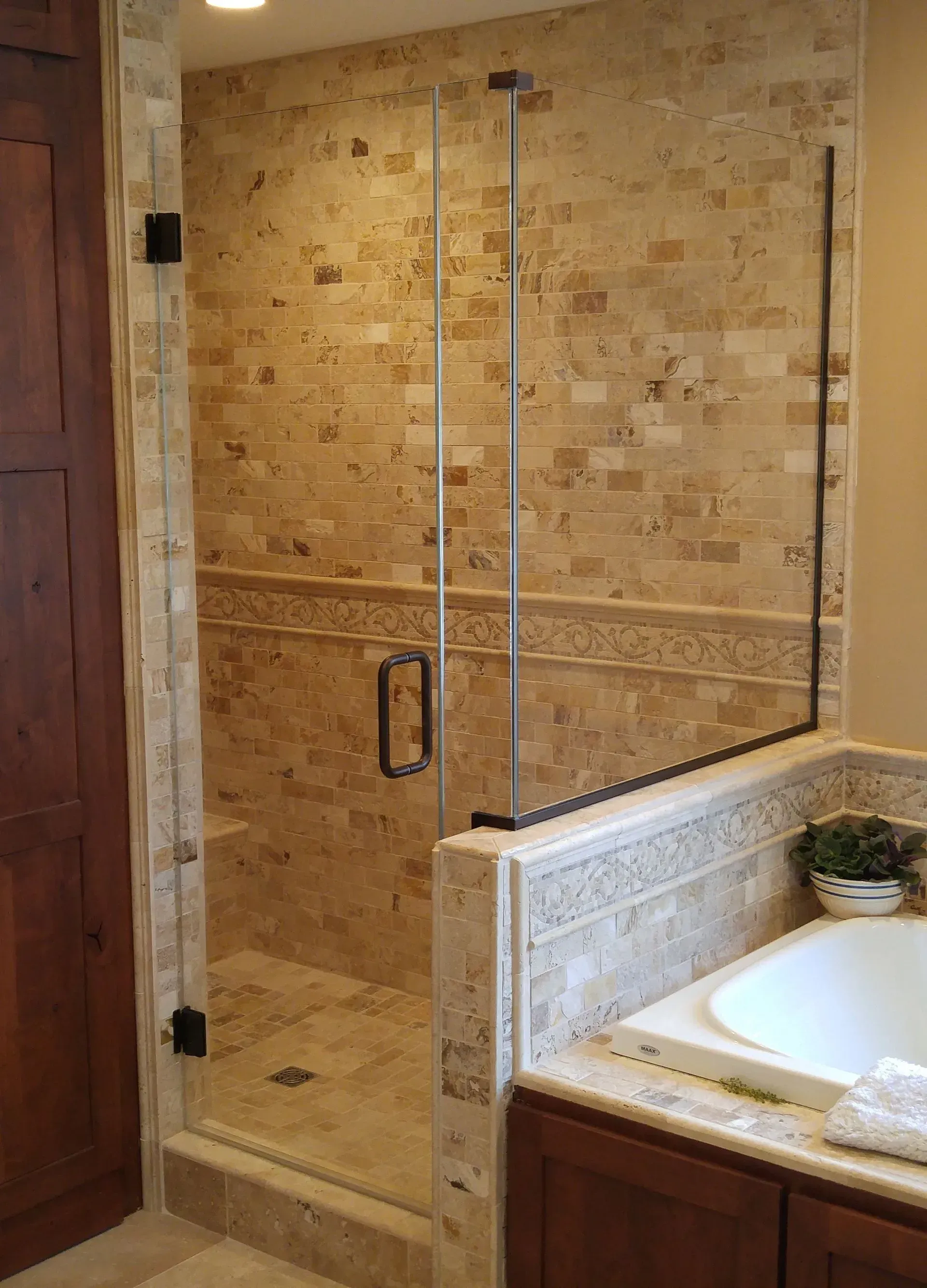 A bathroom with a walk in shower and a tub.