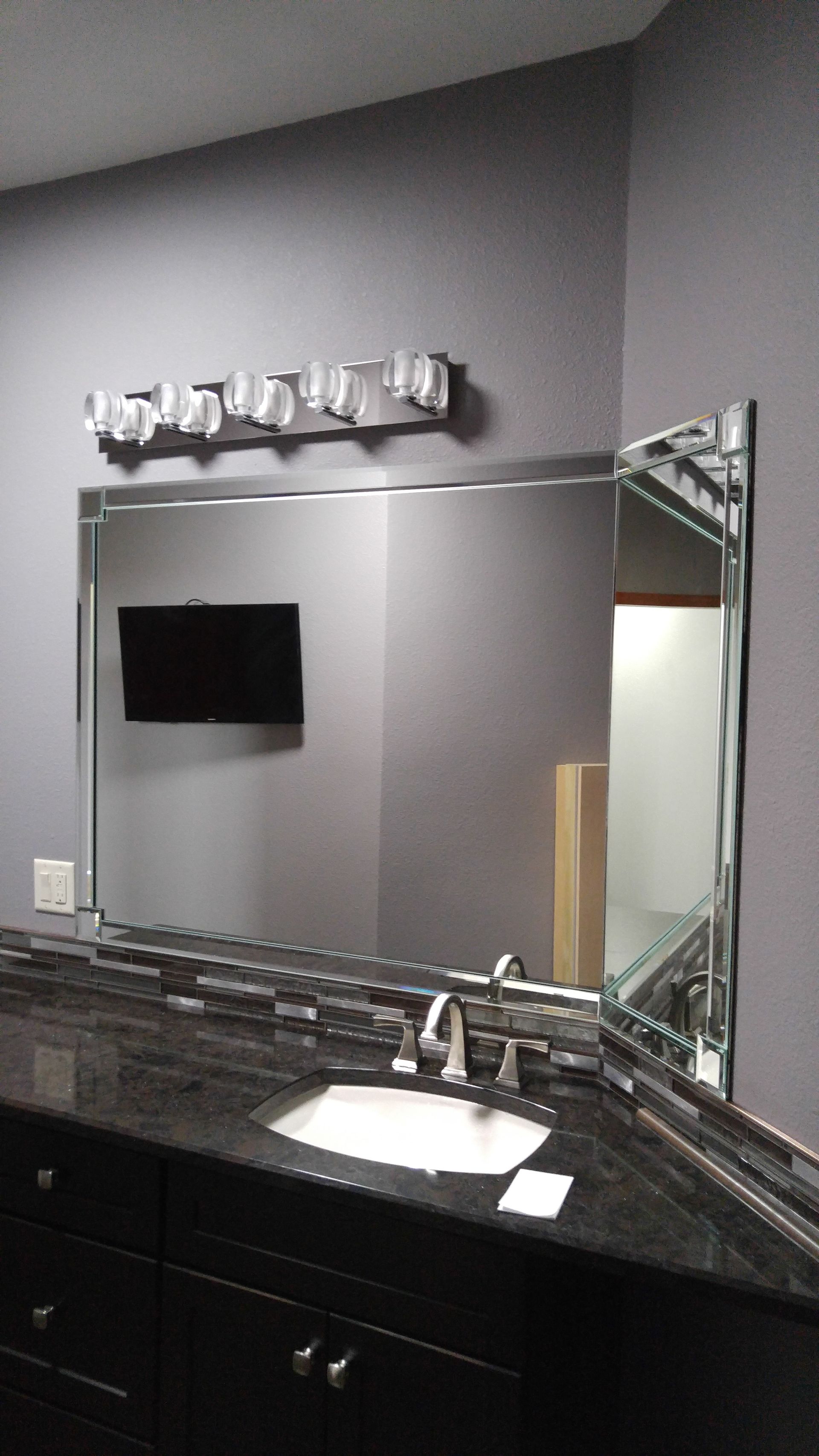 A bathroom with a large mirror and a sink.