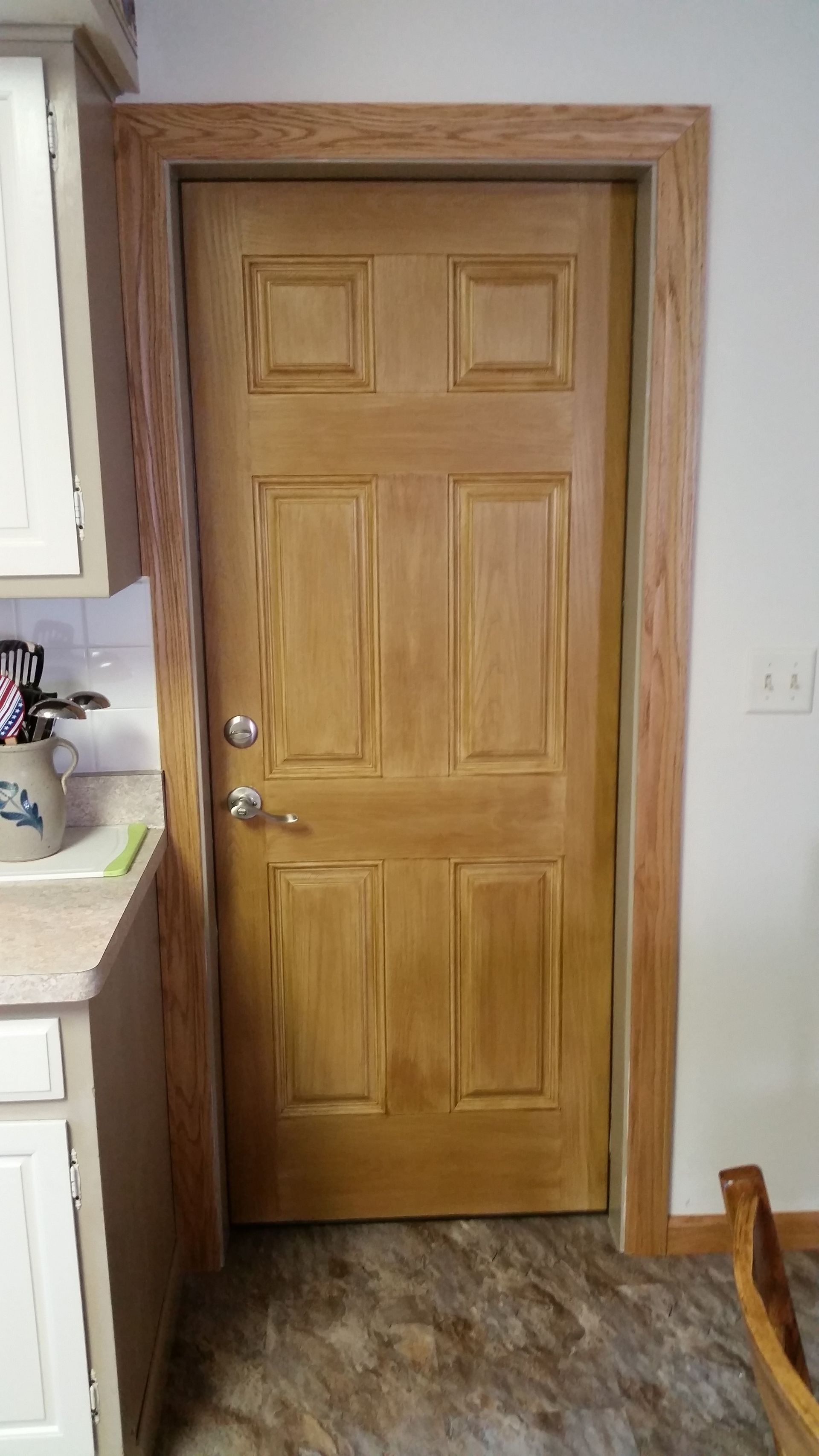 A wooden door in a kitchen next to a sink.