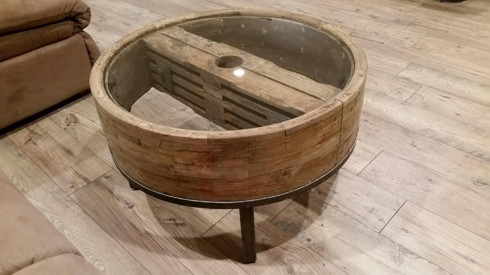 A wooden coffee table with a glass top is sitting on a wooden floor.