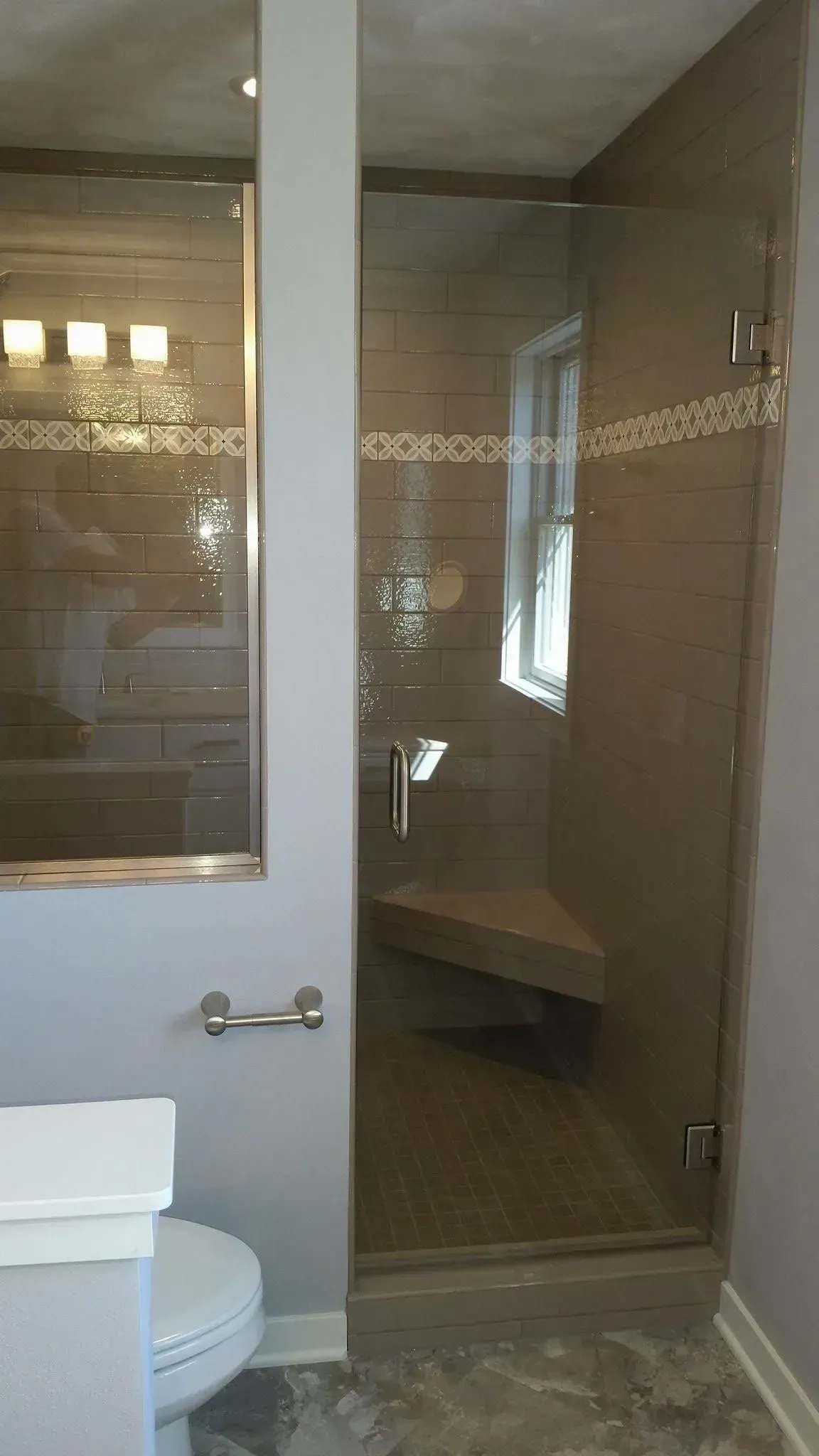 A bathroom with a toilet , sink and shower with a glass door.