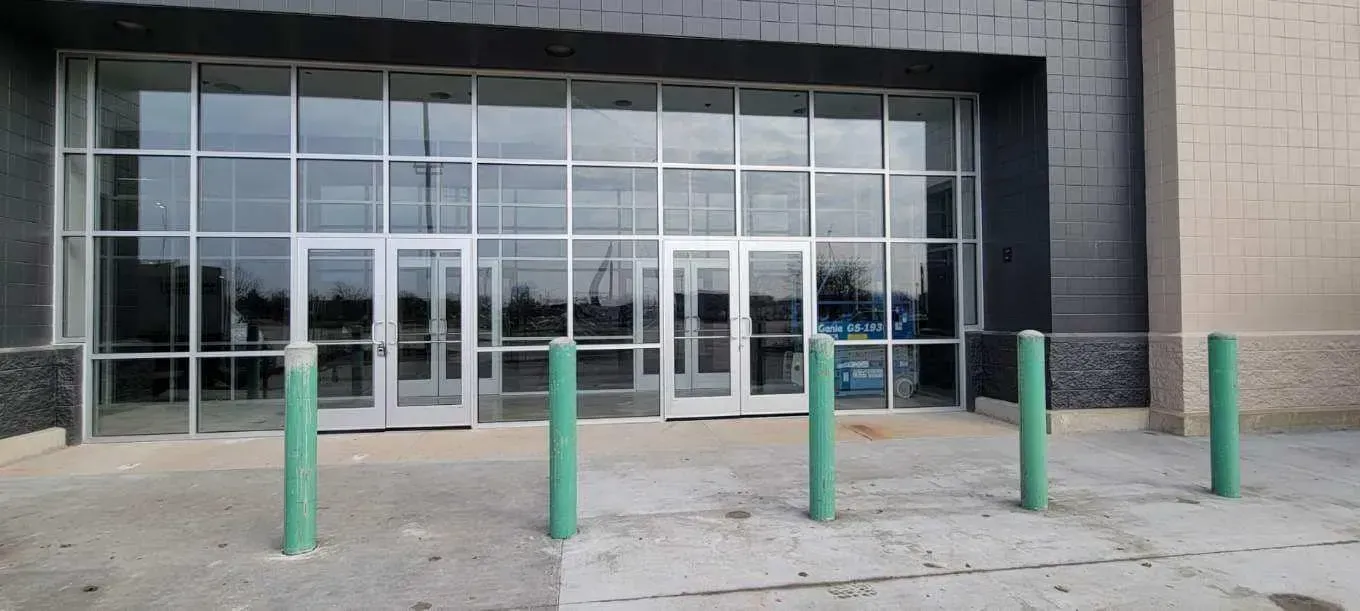 A large building with a lot of windows and green poles in front of it.