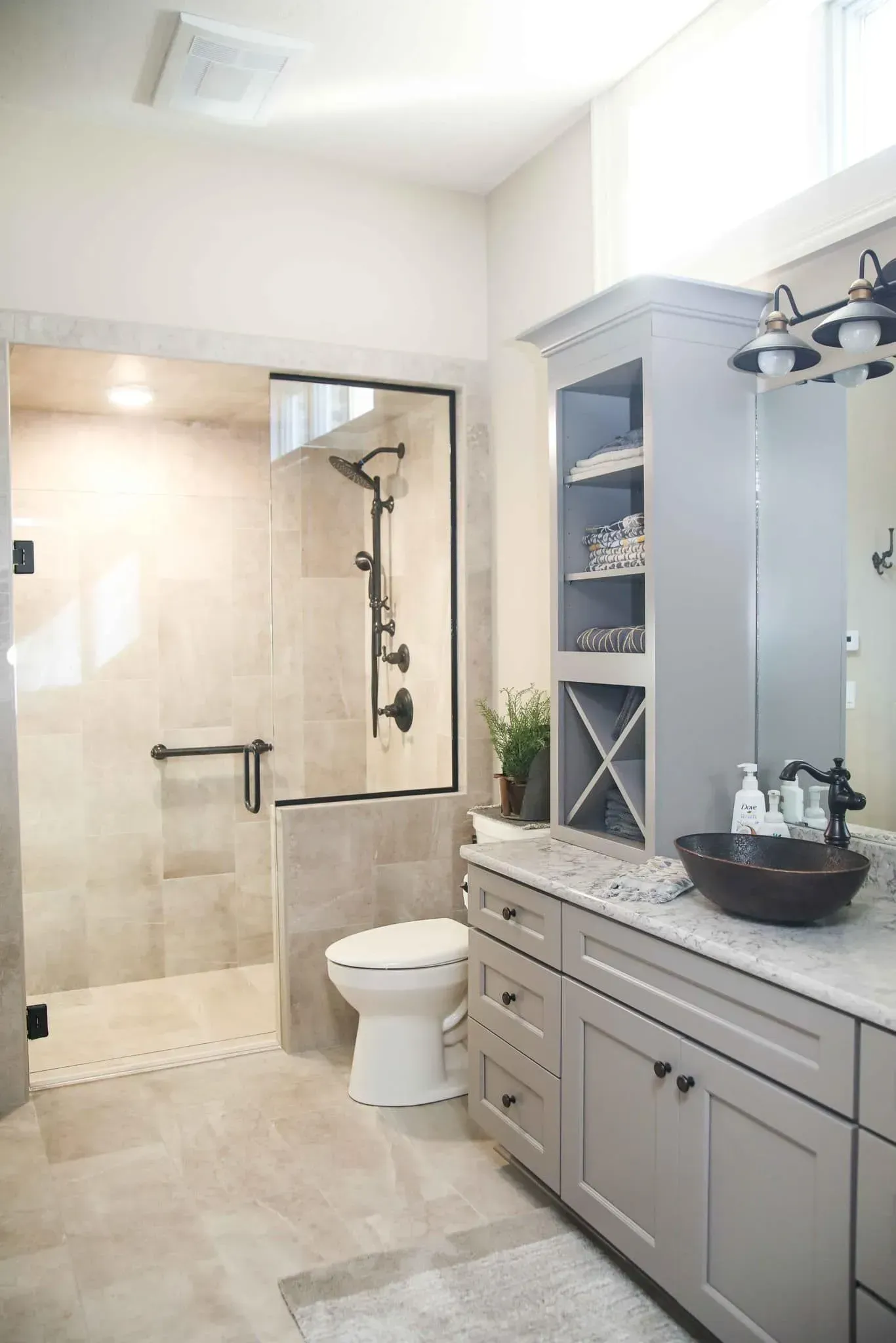 A bathroom with a toilet , sink , mirror and walk in shower.