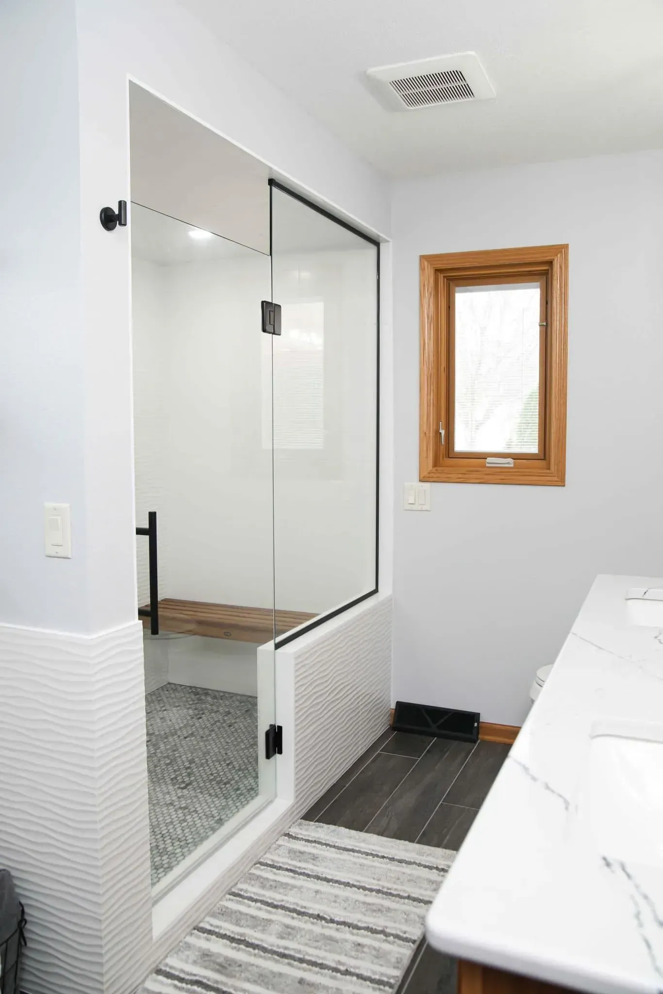 A bathroom with a walk in shower and a window.