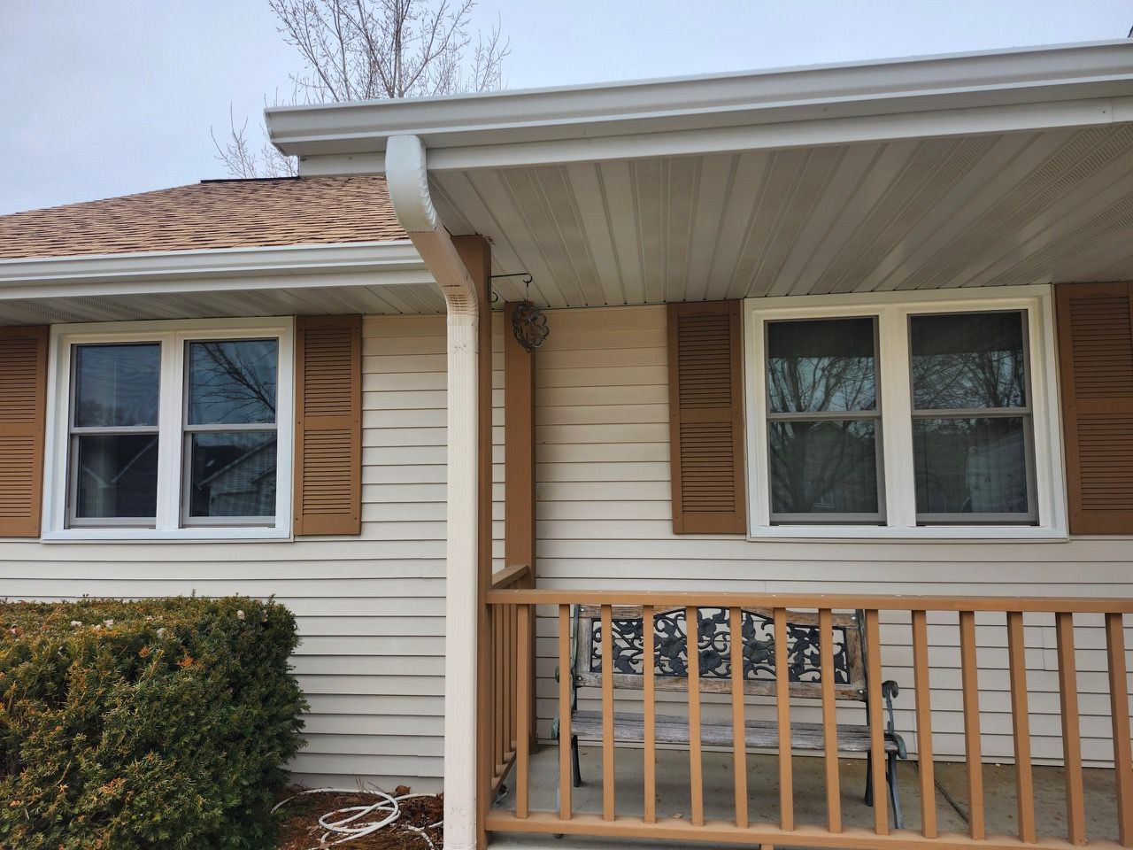 A white house with brown shutters and a porch