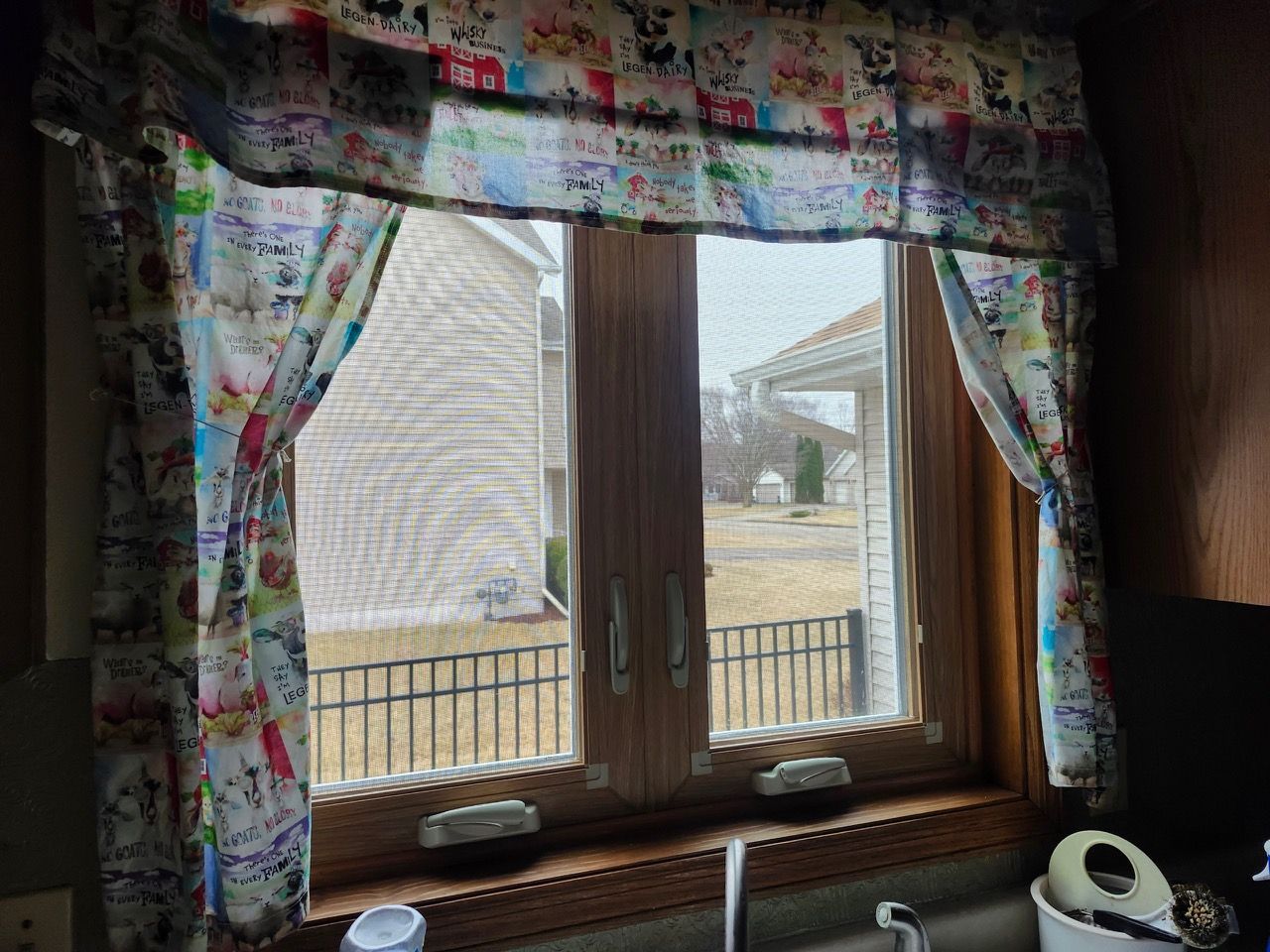 A kitchen window with colorful curtains and a sink.