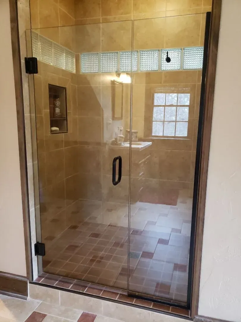 A bathroom with a glass shower door and a sink.